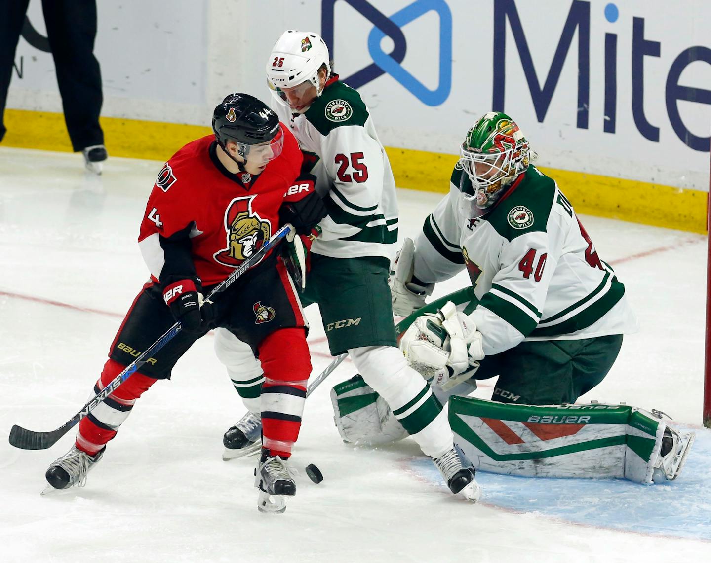 Ottawa Senators' Jean-Gabriel Pageau (44) and Minnestoa Wild's Jonas Brodin (25) battle for the puck as Wild goaltender Devan Dubnyk (40) watches during the second period of an NHL hockey game Tuesday, March 15, 2016, in Ottawa, Ontario. (Fred Chartrand/The Canadian Press via AP)