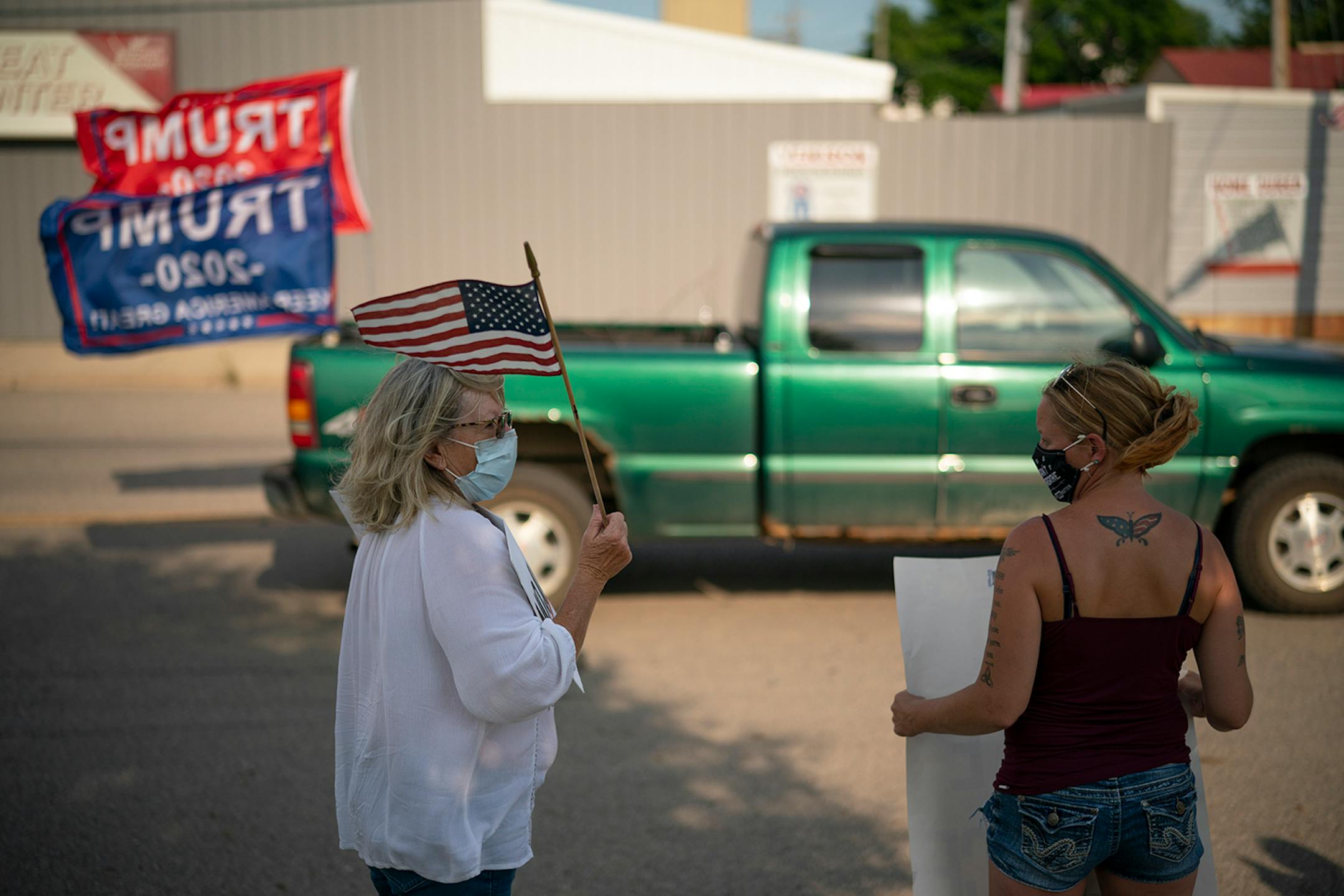 Linda Nelson, left, and Nicole Meyer, right, visited while demonstrating with about 45 other social justice supporters Thursday afternoon as a pro-Trump pickup drove past.