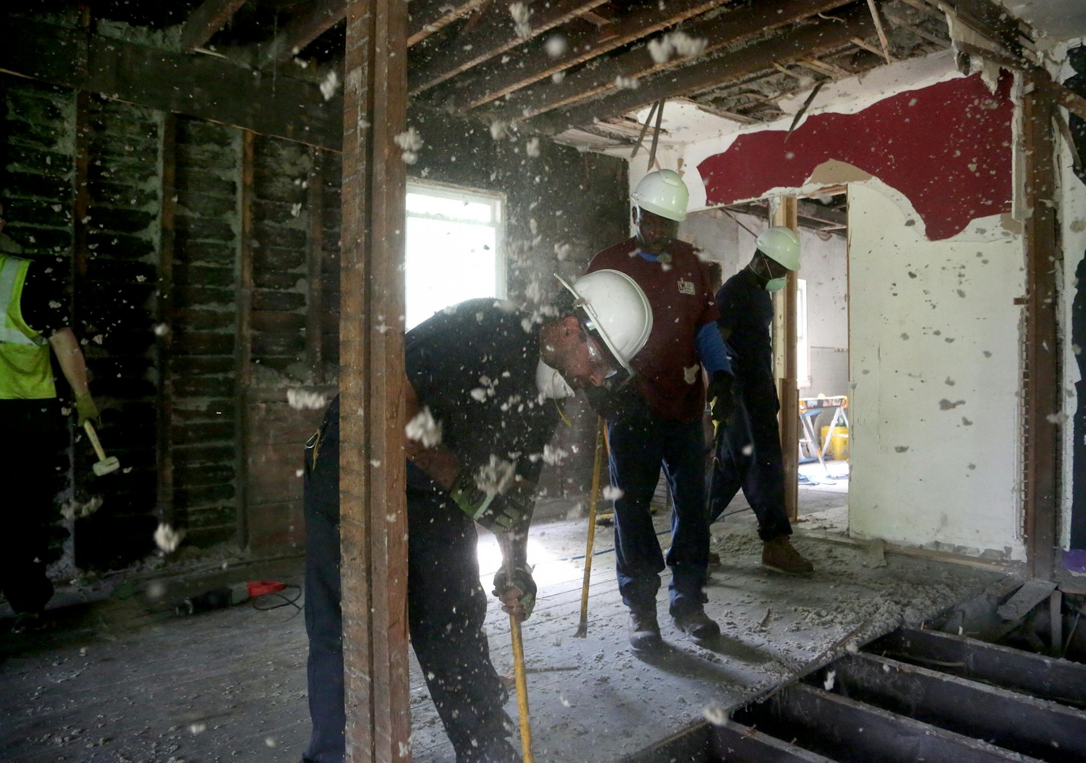 Old insulation falls from the ceiling as workers for Better Homes Minnesota, a non-profits that assists men in the community in gaining employment while helping protecting the environment, worked to disassemble a house slated for with most of the materials will be reused and seen Tuesday, July 18, 2017, in Roseville, MN.