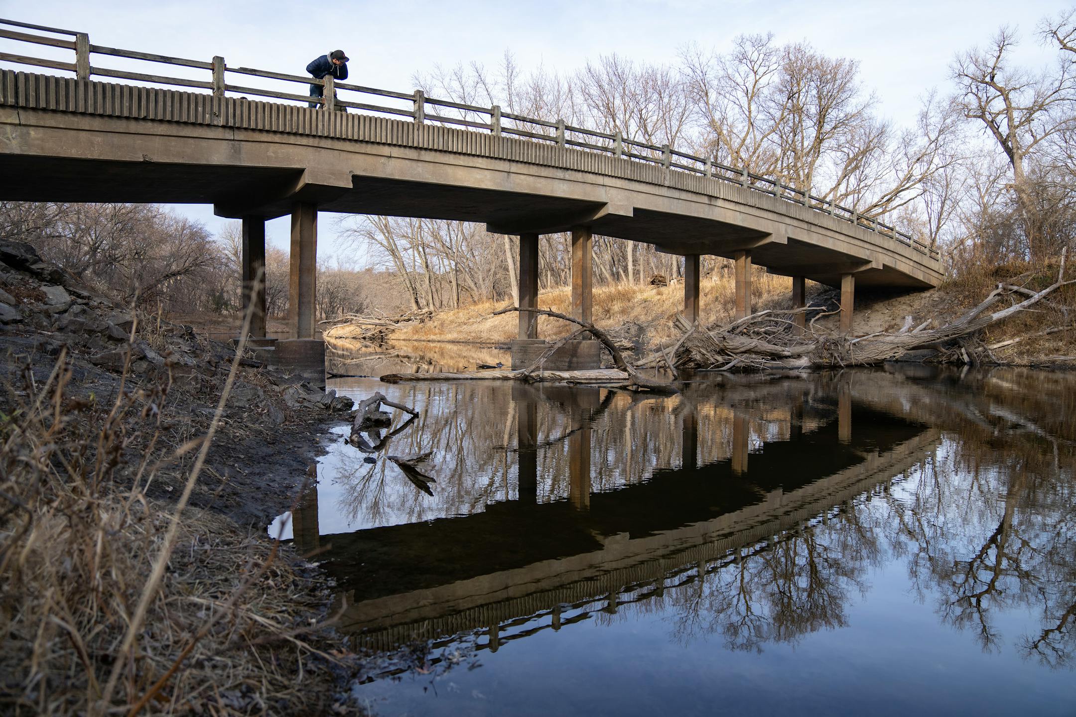 A ark visitor leans over a bridge leading to Pike Island to look for beavers Wednesday, Nov. 22, 2023, at Fort Snelling State Park in St. Paul, Minn. All state park admission is free on Friday, Nov. 24, 2023. ]