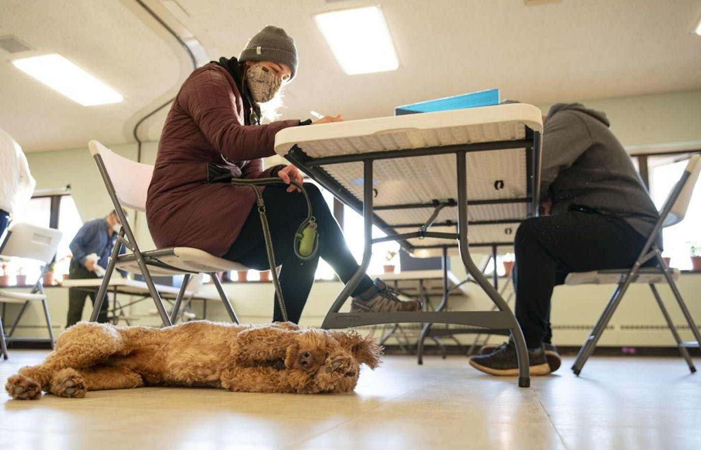 Casey Scrignoli filled out her ballot while her dog, Chester, played on the floor at First United Methodist Church in Duluth on Tuesday morning.