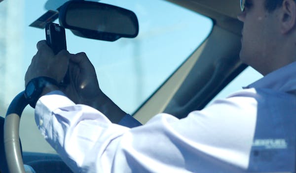 A man looks at his phone while driving.