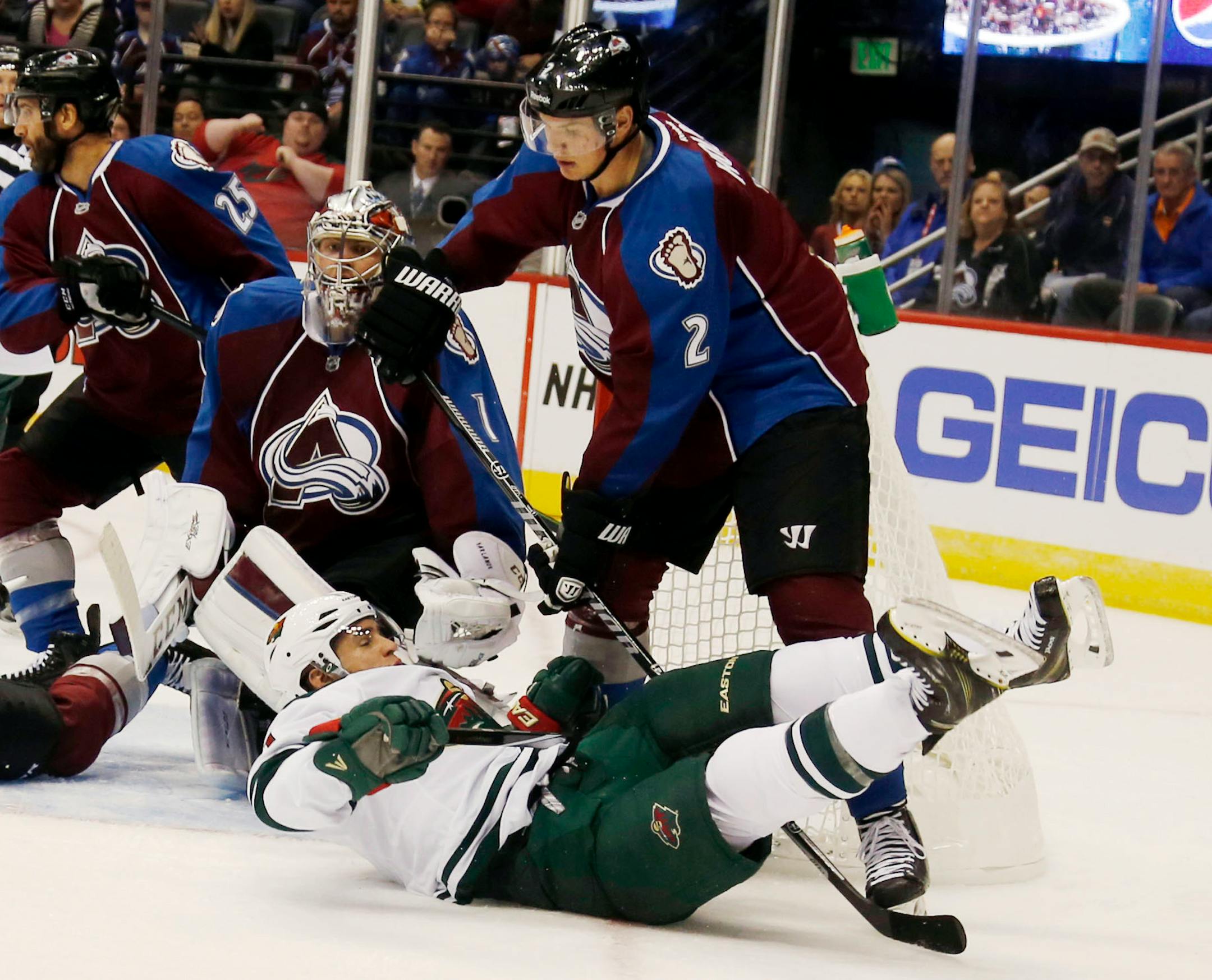 Minnesota Wild left wing Zach Parise, front, falls to the ice after being hit by Colorado Avalanche defensman Nick Holden while redirecting a shot on Avalanche goalie Semyon Varlamov, back, of Russia, during a Wild power play late in the first period of a hockey game in Denver on Saturday, Oct. 11, 2014. (AP Photo/David Zalubowski)
