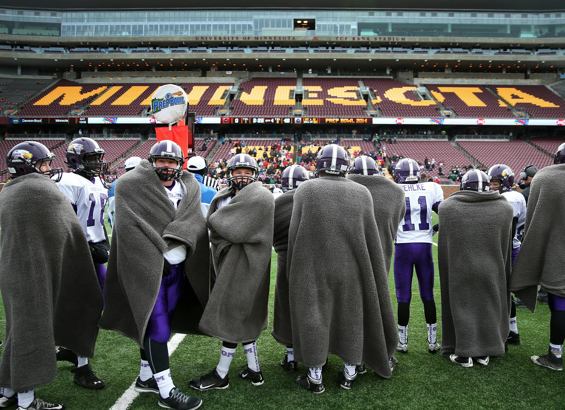 Grand Meadow players stay warm with fleece blankets on the sidelines. ] LEILA NAVIDI leila.navidi@startribune.com / BACKGROUND INFORMATION: Edgerton/Ellsworth and Grand Meadow face off in the nine-man State Championship game at TCF Bank Stadium in Minneapolis on Friday, November 21, 2014.