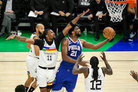 Philadelphia 76ers center Joel Embiid (21) goes up for a shot past Minnesota Timberwolves center Naz Reid (11) during the second half of an NBA basket