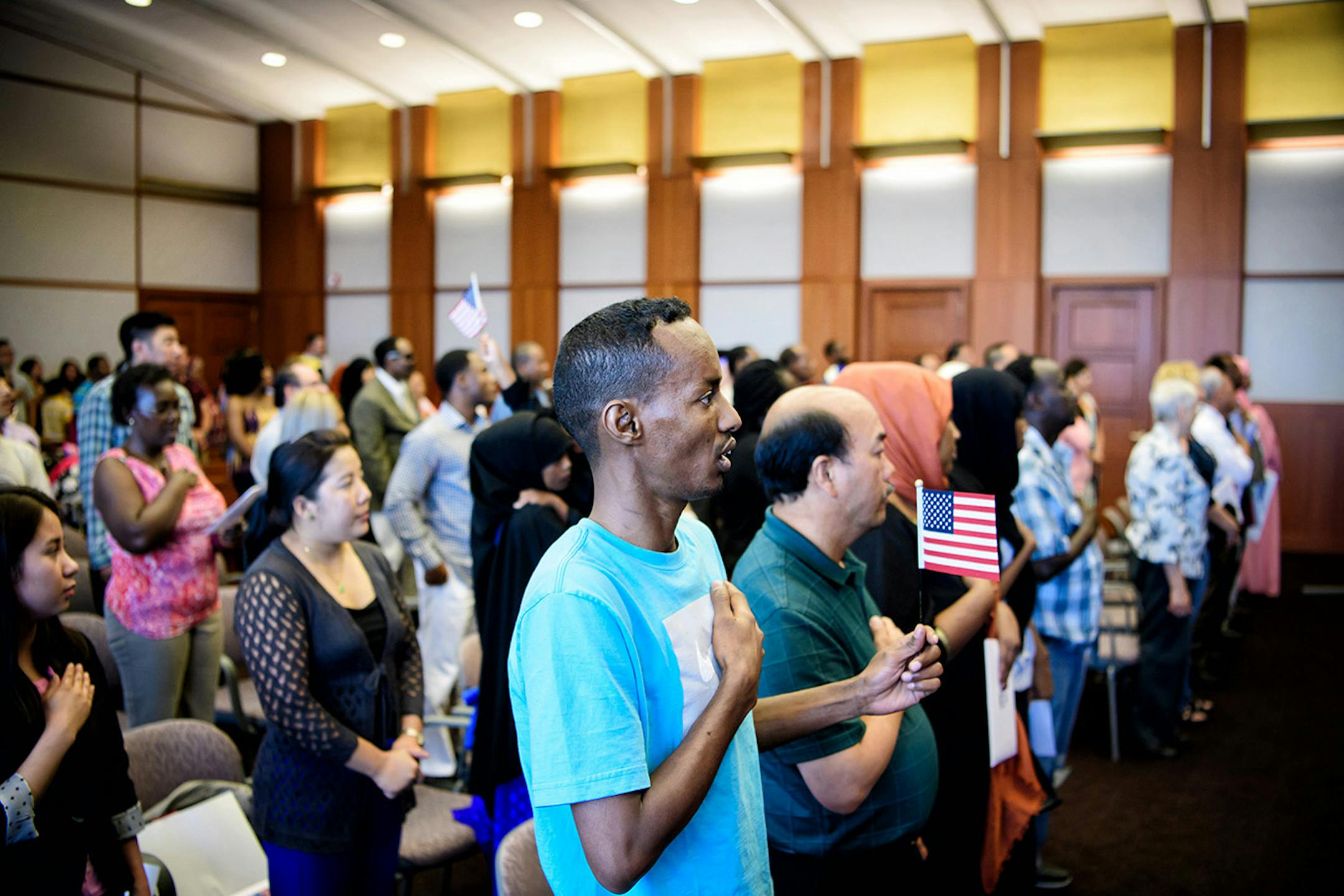 Farah Jama sang the Star Spangled Banner. He was among the 55 people from 22 countries who became U.S. citizens.