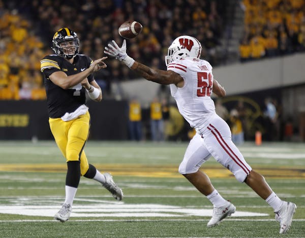 Iowa quarterback Nate Stanley, left, throws the ball as Wisconsin linebacker Zack Baun, right, pressures during the second half of an NCAA college foo