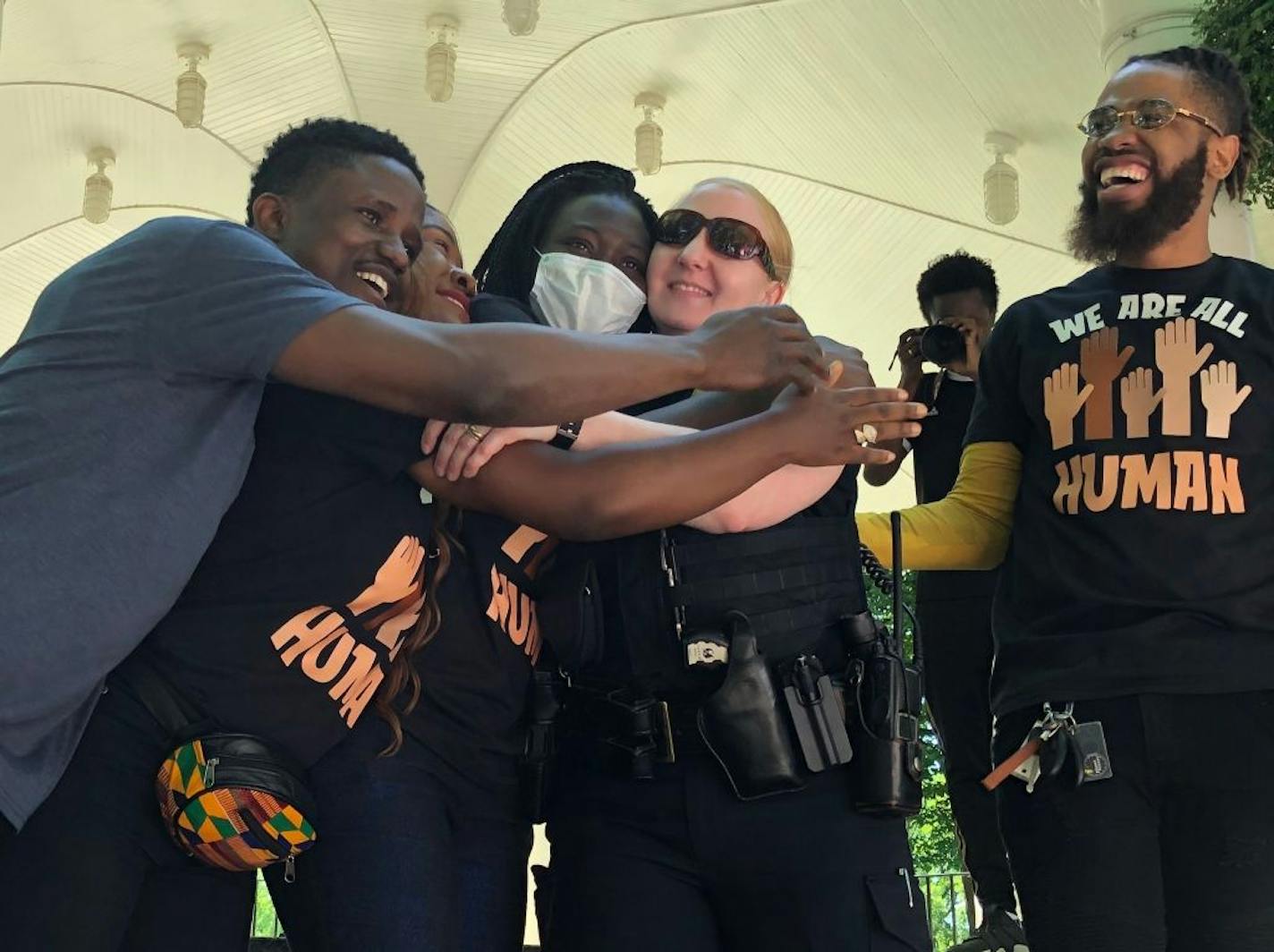 Sgt. Cristie Jacobsen, center, of the Fargo Police Department, receives hugs from organizers at the end of a George Floyd memorial in Fargo, N.D., Friday, June 5, 2020. Jacobson was brought up to the stage at Island Park while musicians performed the song "Lean on Me." Hundreds of people attended the peaceful rally that included speeches, live music and dancing.