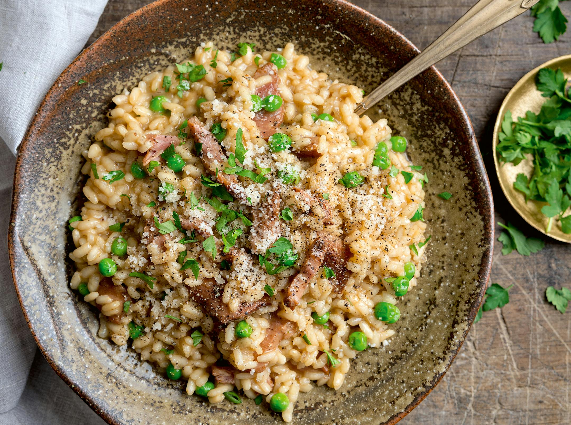 A bowl of creamy risotto with ham and peas.