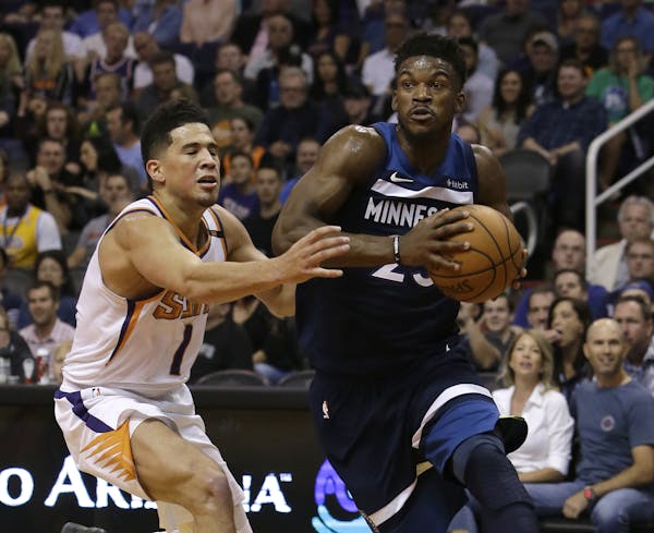 Minnesota Timberwolves guard Jimmy Butler drives past Phoenix Suns guard Devin Booker (1) in the first half during an NBA basketball game, Saturday, N
