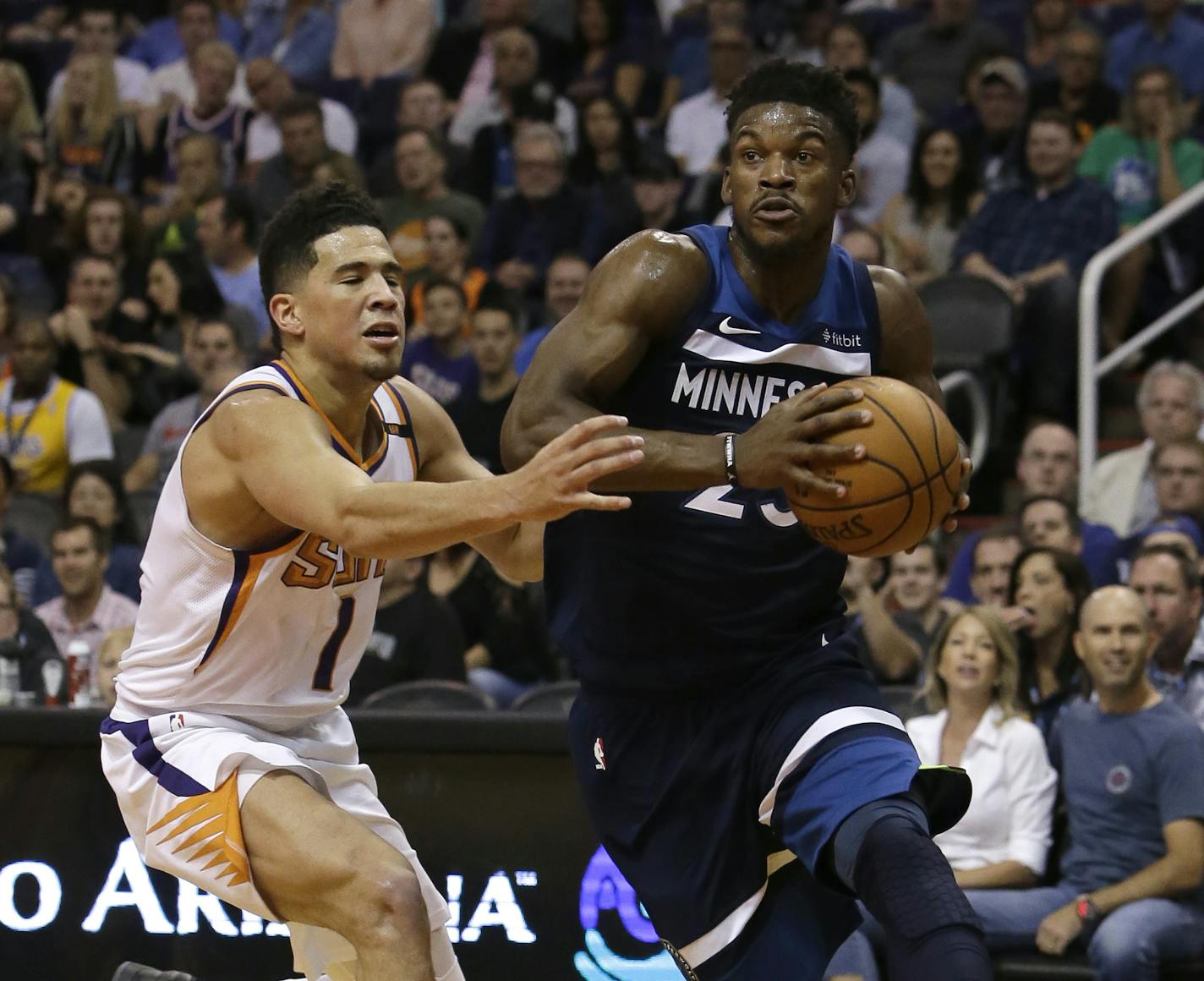 Minnesota Timberwolves guard Jimmy Butler drives past Phoenix Suns guard Devin Booker (1) in the first half during an NBA basketball game, Saturday, Nov 11, 2017, in Phoenix. (AP Photo/Rick Scuteri)