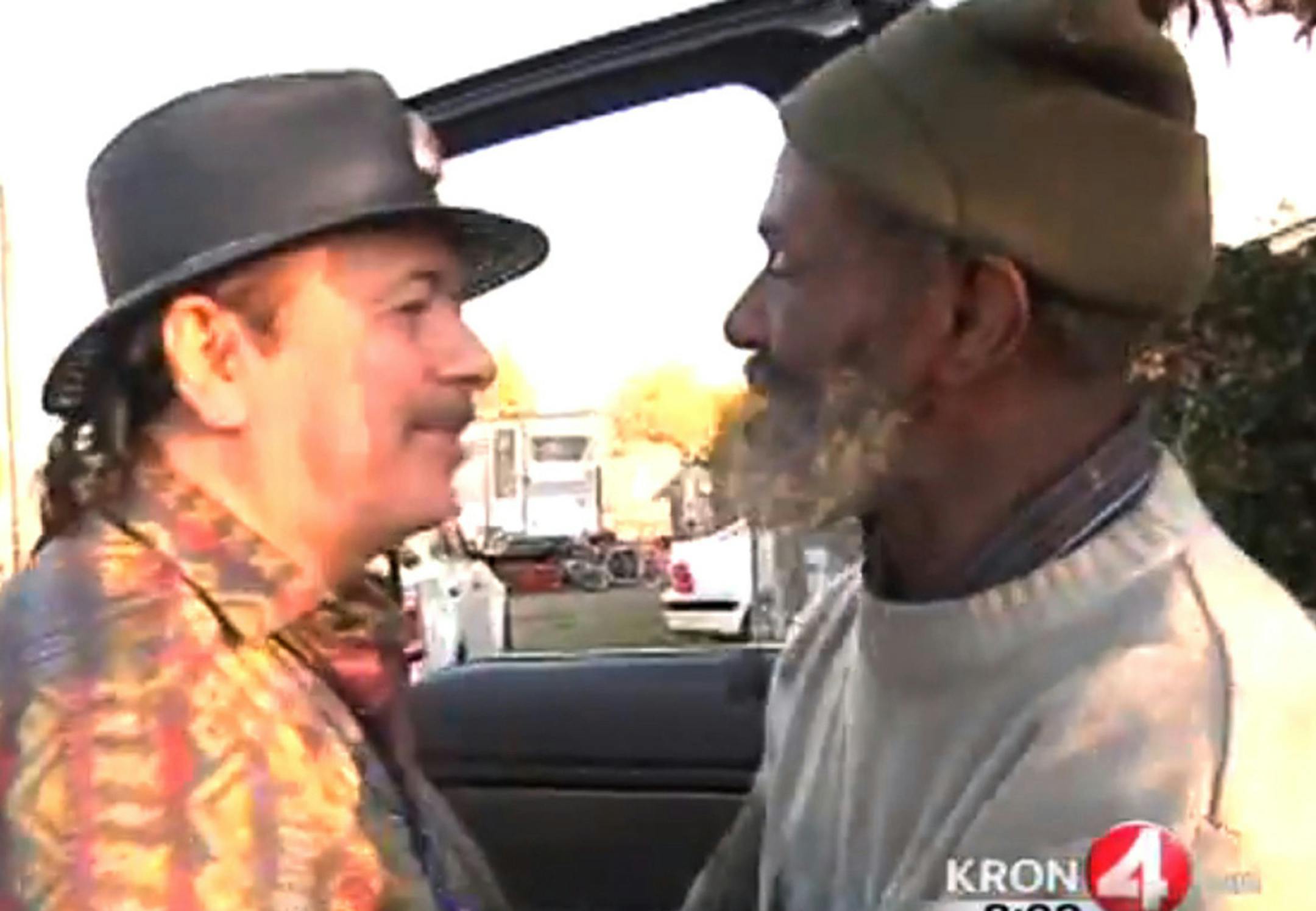 In this Friday, Dec. 20, 2013 frame grab from video provided by KRON-TV, famed rock guitarist Carlos Santana, left, greets his former bandmate Marcus Malone on the streets of Oakland, Calif. It had been decades since Santana had seen Malone, who now describes himself as homeless and living on the streets of Oakland. KRON-TV reporter Stanley Roberts ran into percussionist Marcus "The Magnificent" Malone while working on a story about illegal dumping. Although he initially was skeptical of the hom