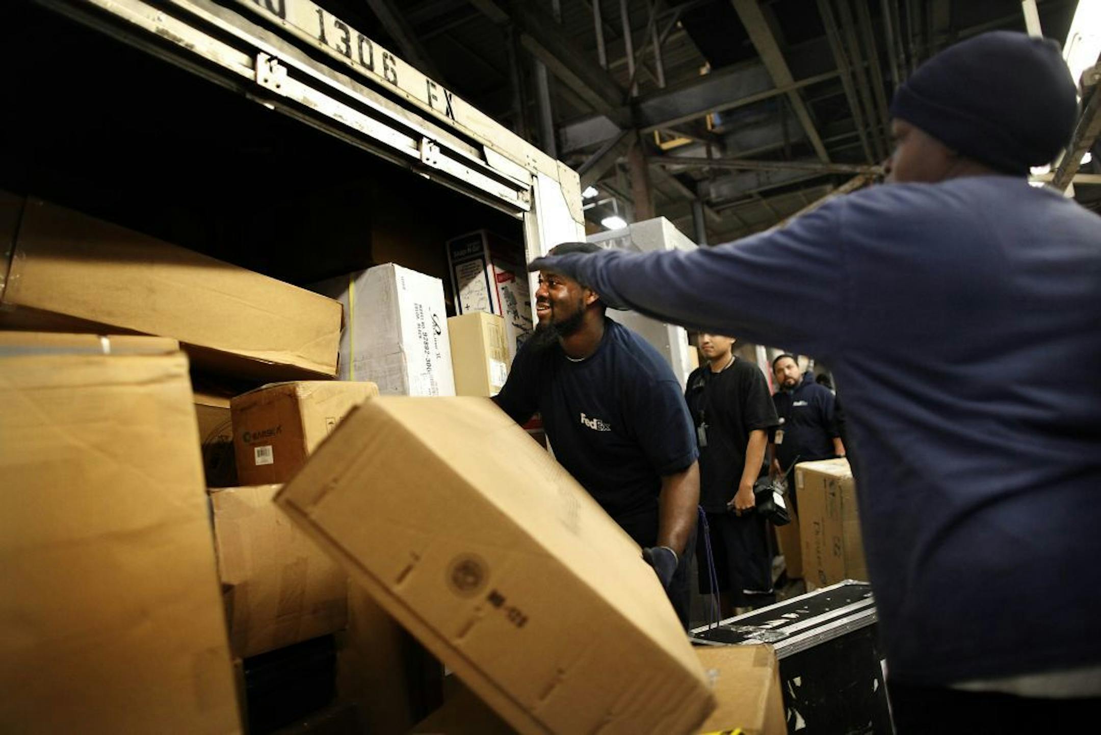 FedEx employees, including Marcell G. Haythorne, center, move packages on the busiest day of the year inside the sorting and shipping hub at Los Angeles International Airport on Monday, Dec. 15, 2014.