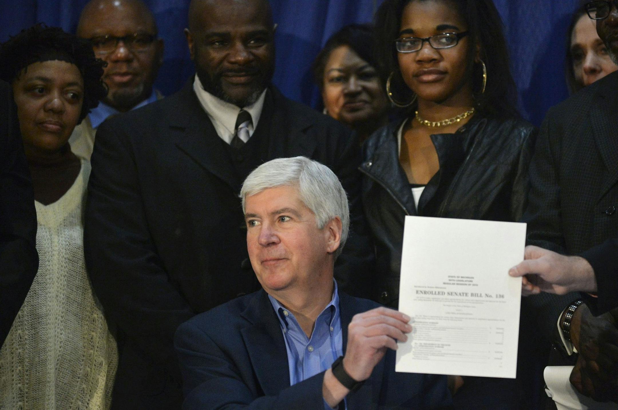 Gov. Rick Snyder displays the $30 million budget supplemental Water Bill during a news conference on Friday, Feb. 26, 2016 at University of Michigan Flint, Riverfront Banquet Center in Flint. Snyder signed the $30 million budget supplemental, reimbursing Flint residents with credits on their water bills for water used for drinking, cooking and bathing. (Rachel Woolf/The Flint Journal-MLive.com via AP) LOCAL TELEVISION OUT; LOCAL INTERNET OUT; MANDATORY CREDIT