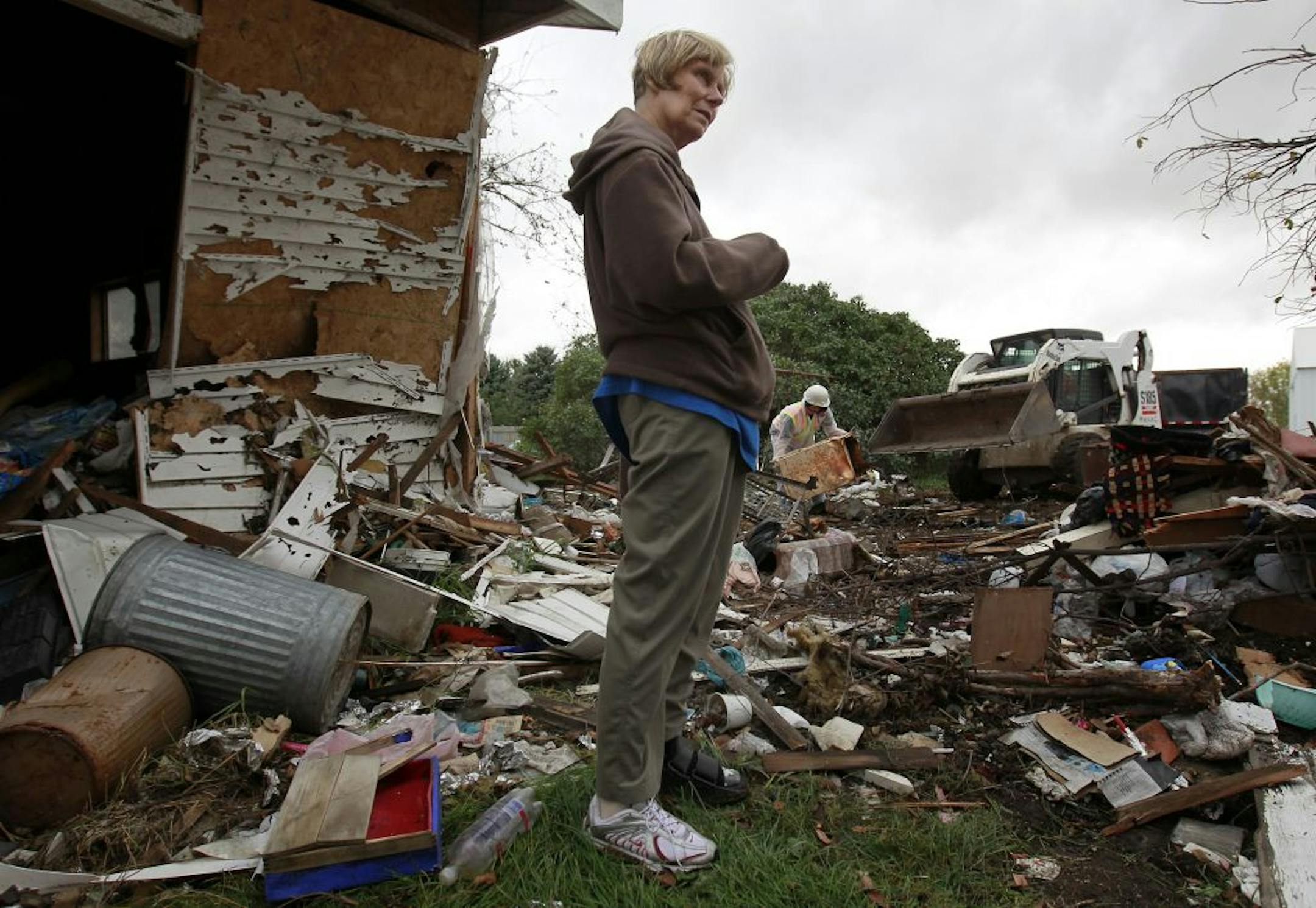 Janice Harms stood by the ruble of her destroyed home as a crew moved the debris into a pile for removal.