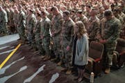 First Lt. Caleb Hjelle and his wife, Regan Hjelle, right, bowed their heads during the benediction of the deployment ceremony for 550 members of the M