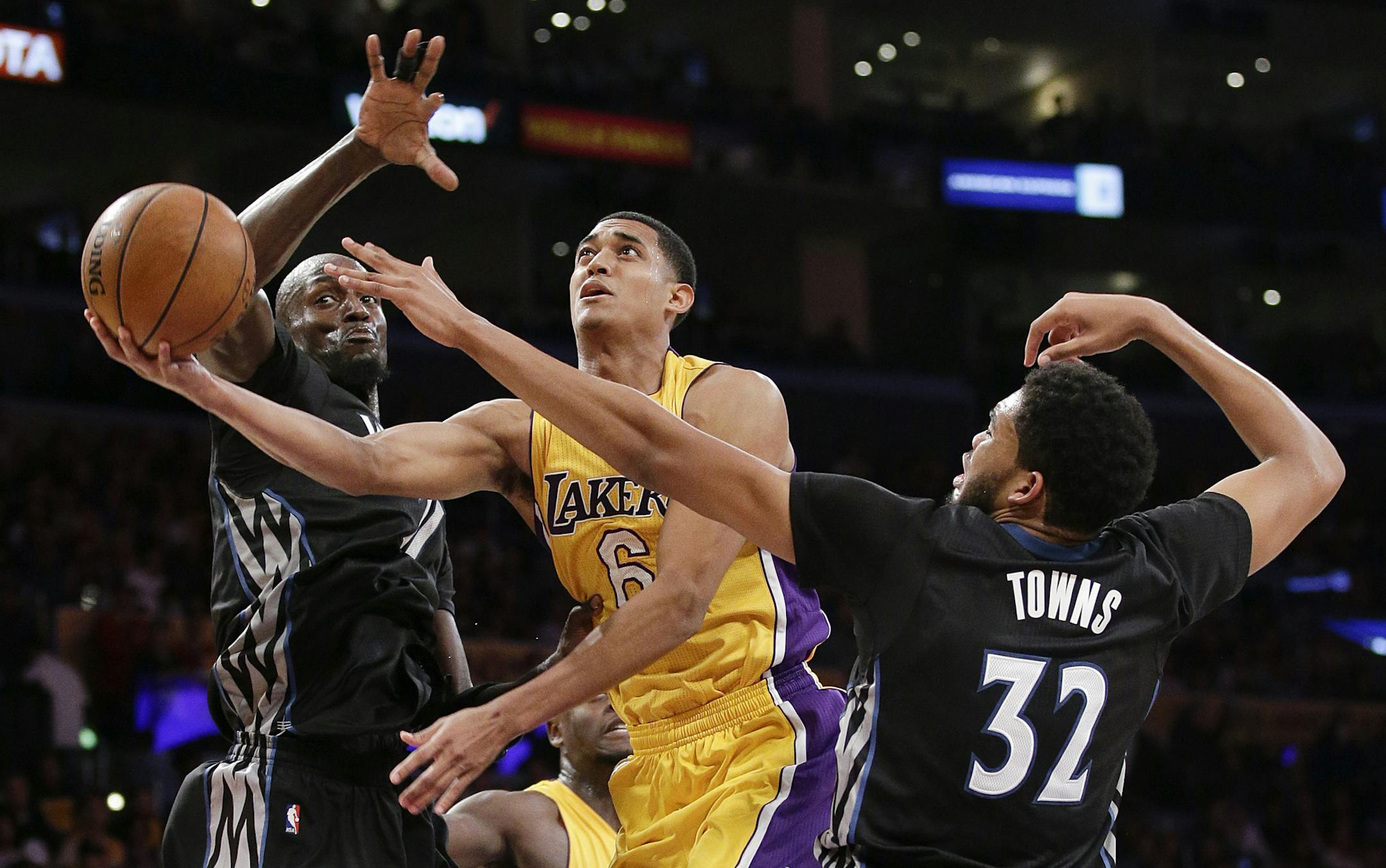Los Angeles Lakers' Jordan Clarkson, center, goes up for a basket under pressure by Minnesota Timberwolves' Karl-Anthony Towns, right, and Kevin Garnett during the first half of an NBA basketball game, Wednesday, Oct. 28, 2015, in Los Angeles. (AP Photo/Jae C. Hong)