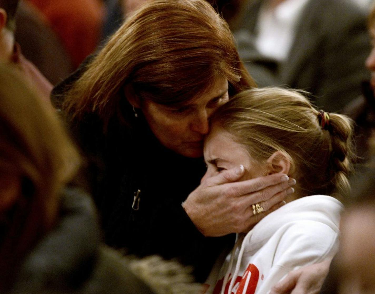 A woman comforts a young girl during a vigil service for victims of the Sandy Hook Elementary shooting, Friday, Dec. 14, 2012, at St. Rose of Lima Roman Catholic Church in Newtown, Conn.