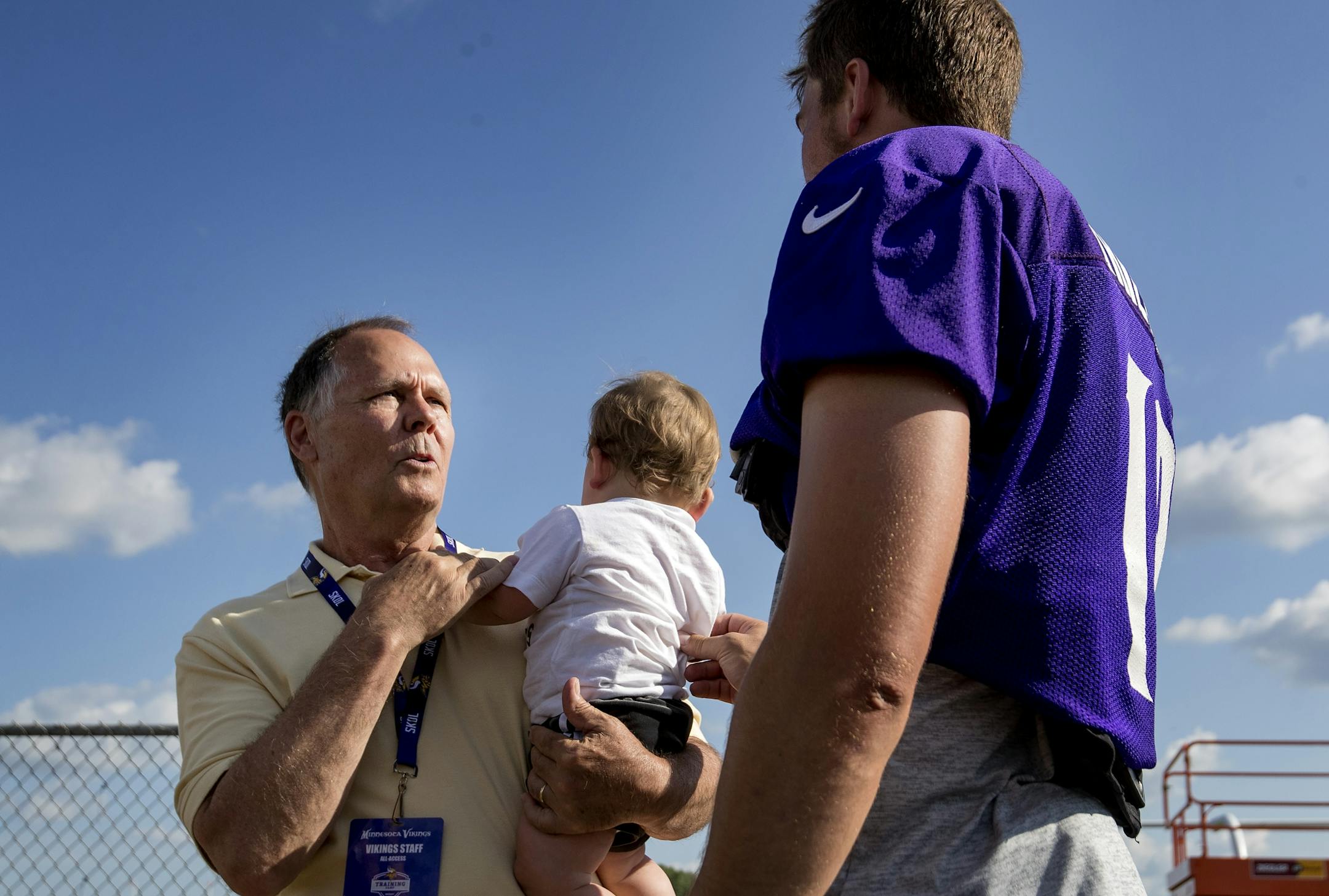 Minnesota Vikings team Champlain Tom Lamphere spoke to receiver Adam Thielen as he held Thielen's son Asher at the end of the afternoon practice.