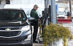 Dennis Bendrick, right, put the gas pump back after putting in gas for customer Tara Malafarina, of Homesville, Pa., at Miller’s Gas and Service on 