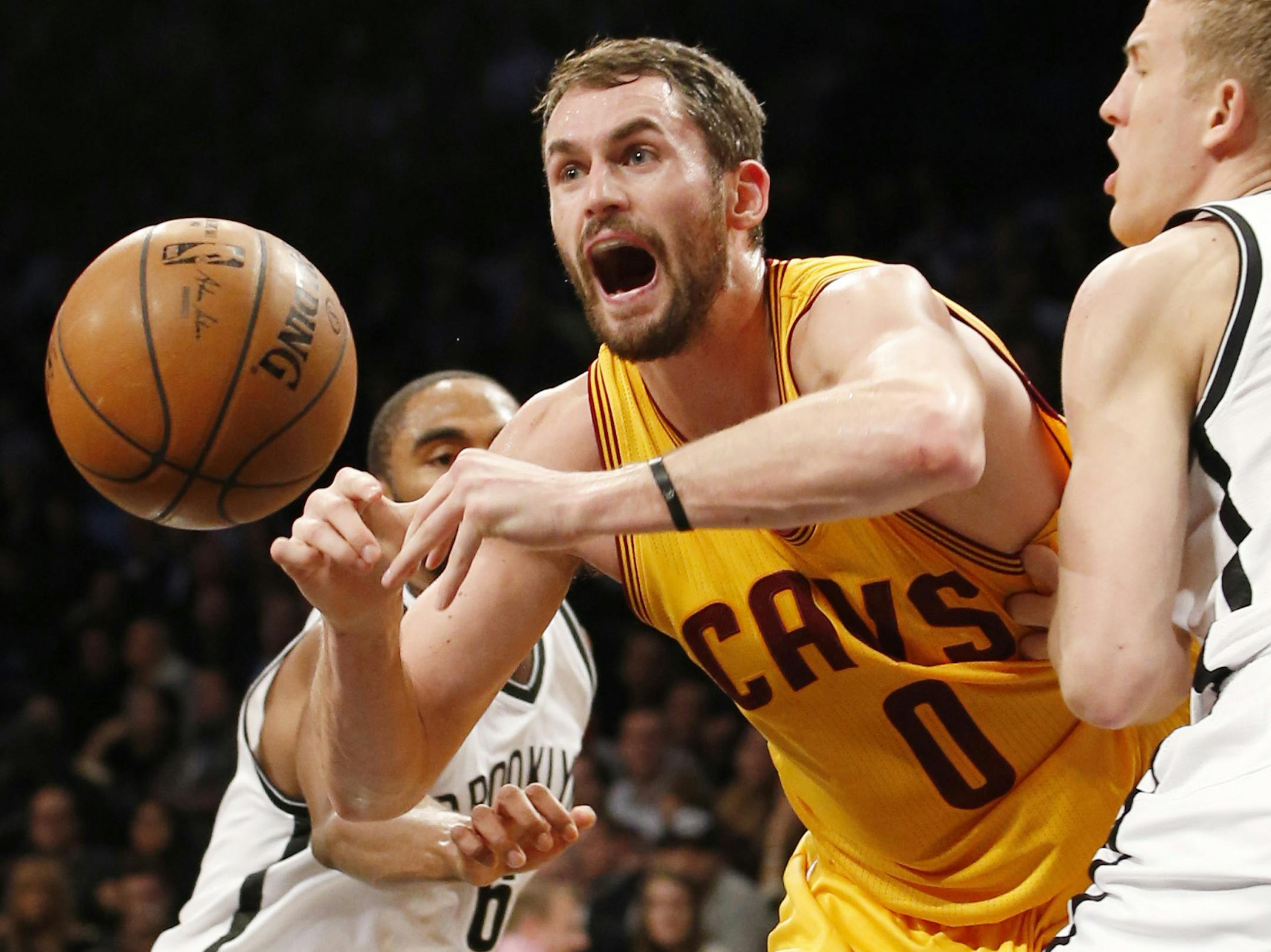 Cleveland Cavaliers forward Kevin Love (0) loses the ball as he is caught between Brooklyn Nets guard Alan Anderson, left, and Nets center Mason Plumlee, right, in the first half of an NBA basketball game at the Barclays Center, Monday, Dec. 8, 2014, in New York. (AP Photo/Kathy Willens) ORG XMIT: NYKW108