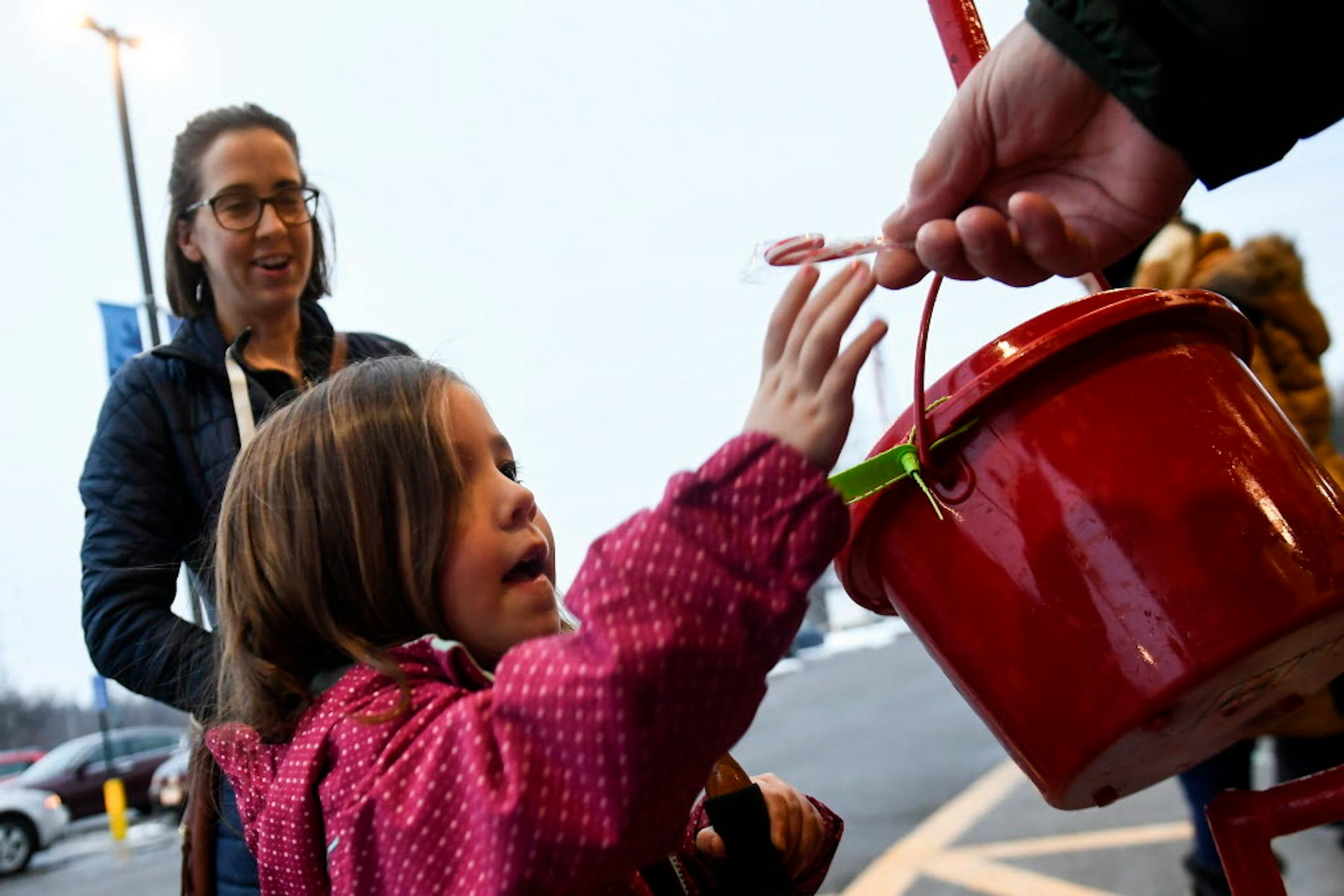 Megan Austin of Roseville watched as bell ringer Charley Brandt handed her daughter, Elise, 4, a candy cane at the Lunds & Byerlys in Roseville.