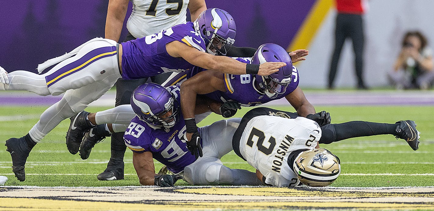 Vikings linebacker Troy Dye (45), left, Vikings linebacker Danielle Hunter (99), center and Vikings linebacker D.J. Wonnum (98) topple Saints quarterback Jameis Winston (2) during the fourth quarter at U.S. Bank Stadium in Minneapolis, Minn., on Friday, Nov. 10, 2023. ] Elizabeth Flores • liz.flores@startribune.com