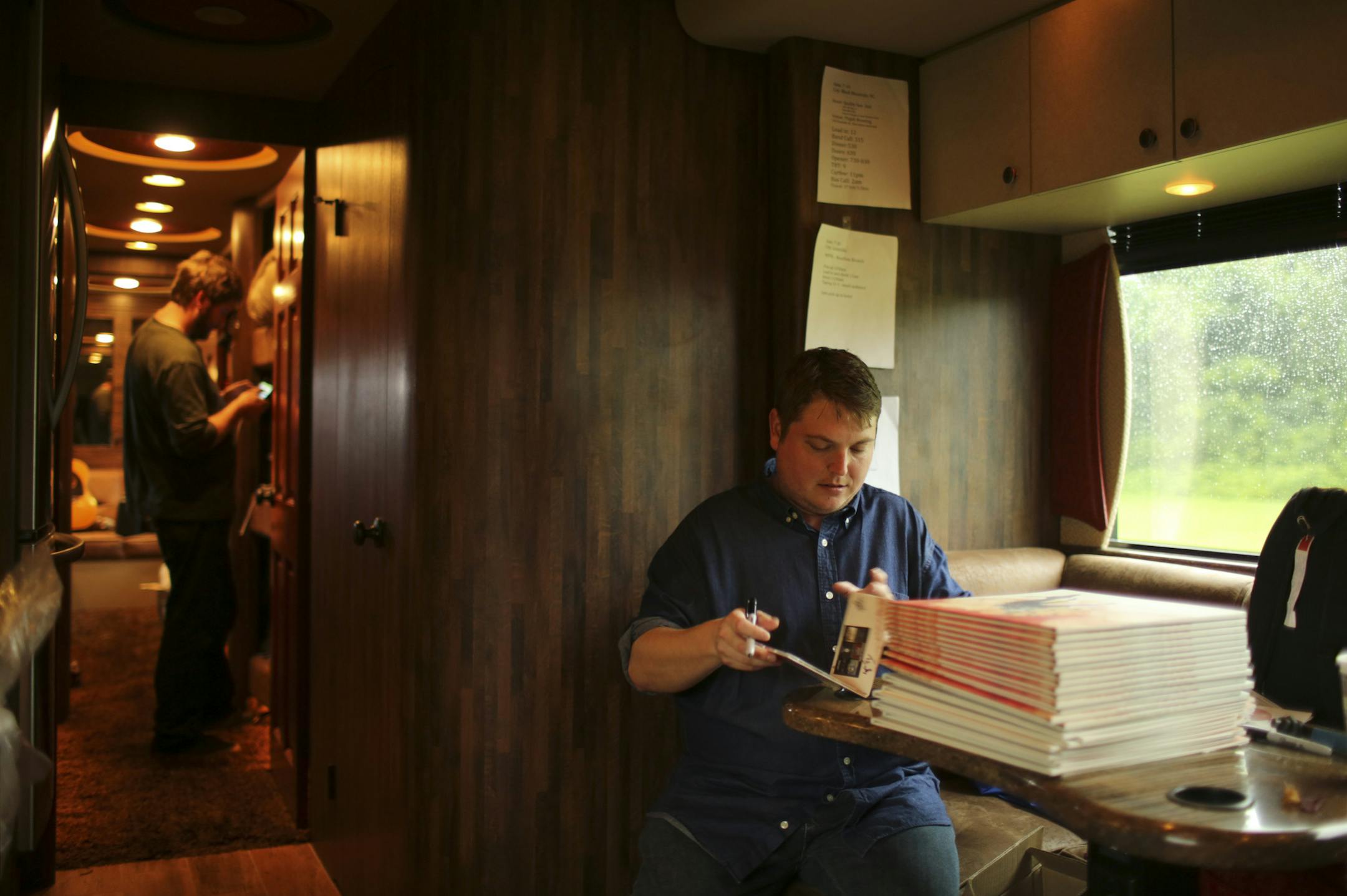 Trampled by Turtles bassist Tim Saxhaug signed CDs on the tour bus before a show in Black Mountain, N.C.