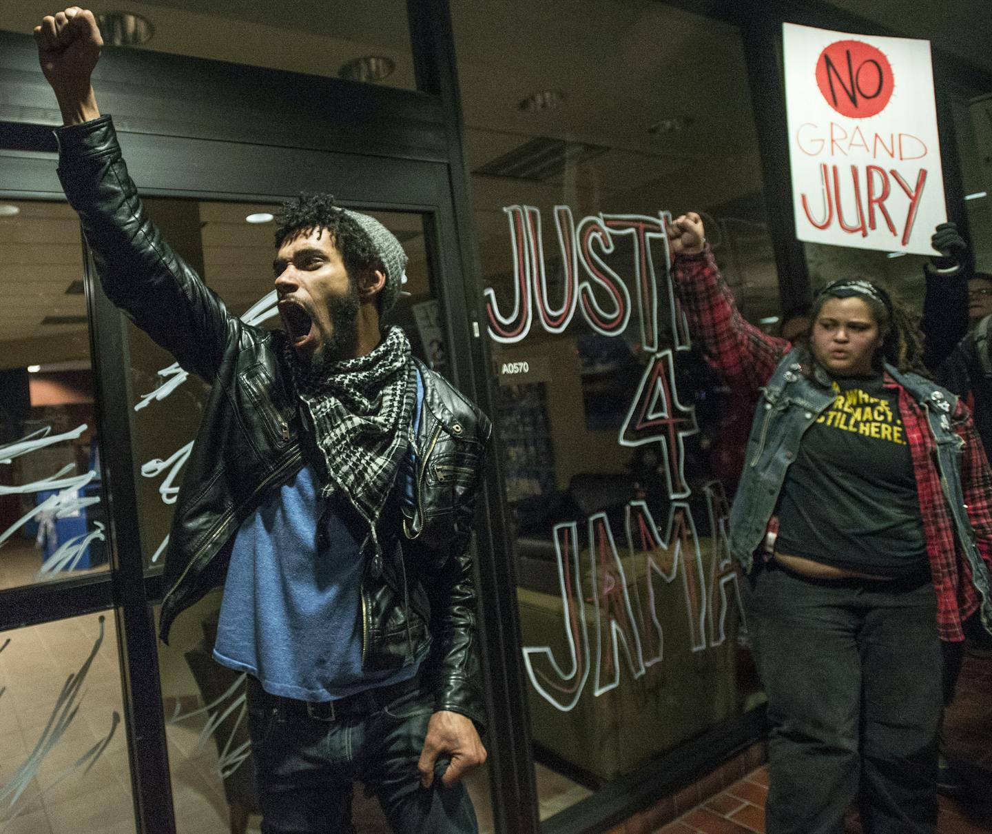 Activist Jacob Ladda chanted with fellow protesters after using a non-permanent marker to write "Justice 4 Jamar" on the windows of Wings Financial Thursday night. ] (AARON LAVINSKY/STAR TRIBUNE) aaron.lavinsky@startribune.com Black Lives Matter held a protest outside Minneapolis City Hall in response to the Minneapolis Police Department's overnight removal of the 4th Precinct encampment on Thursday, Dec. 3, 2015.