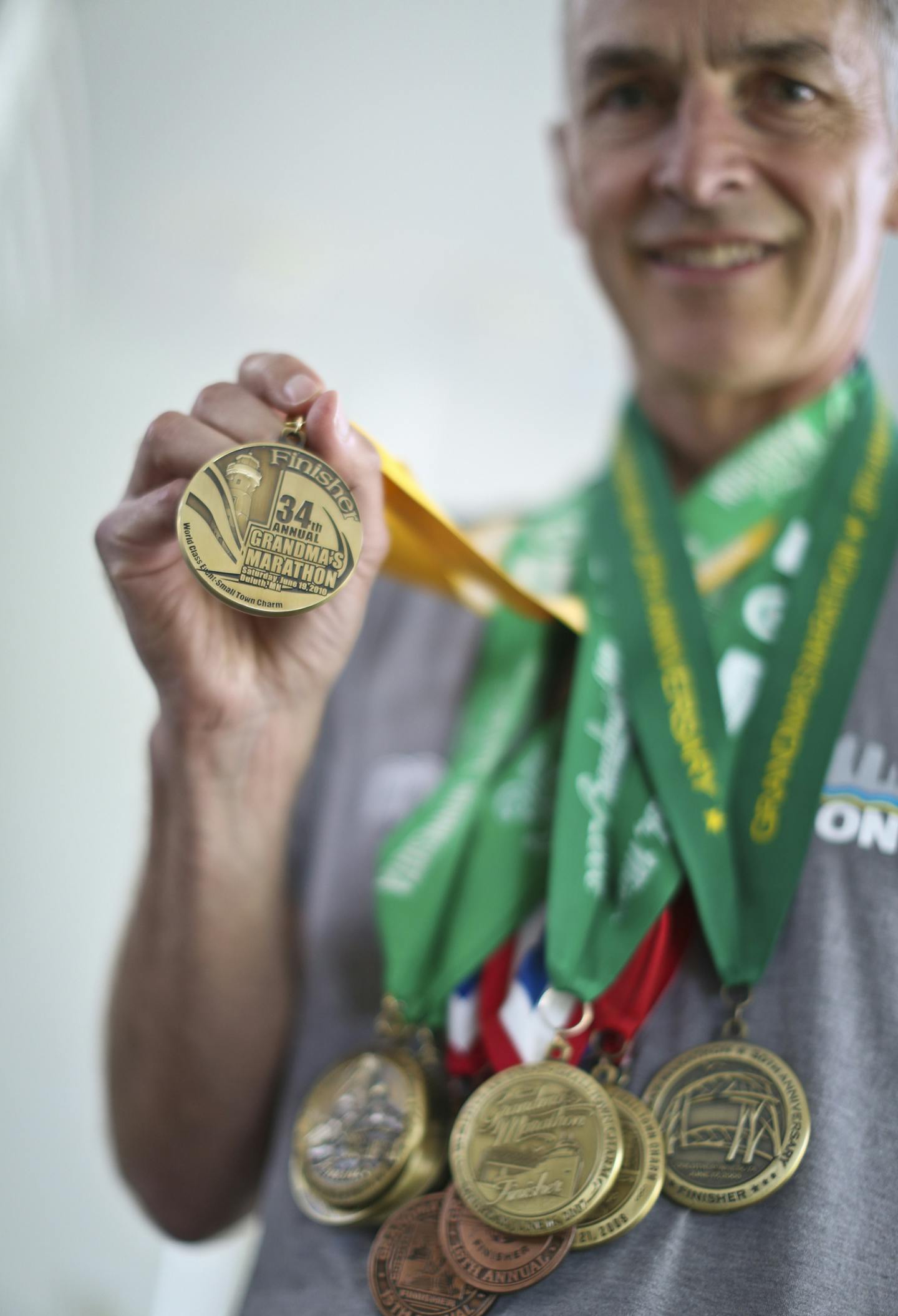 John Naslund is one of three people to have run all 36 Grandma's Marathons. He plans to run the 37th this year on June 22. He was photographed wearing many of the metals he has collected from the race over the years at his home in Bloomington, Minn., on Tuesday, June 18, 2013. ] (RENEE JONES SCHNEIDER * reneejones@startribune.com)