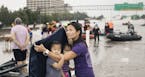 Vi Tran uses a blanket to shield her daughters Olivia, 4, and Eva, 2, from the rain after being evacuated from Houston's Meyerland area, Aug. 27, 2017