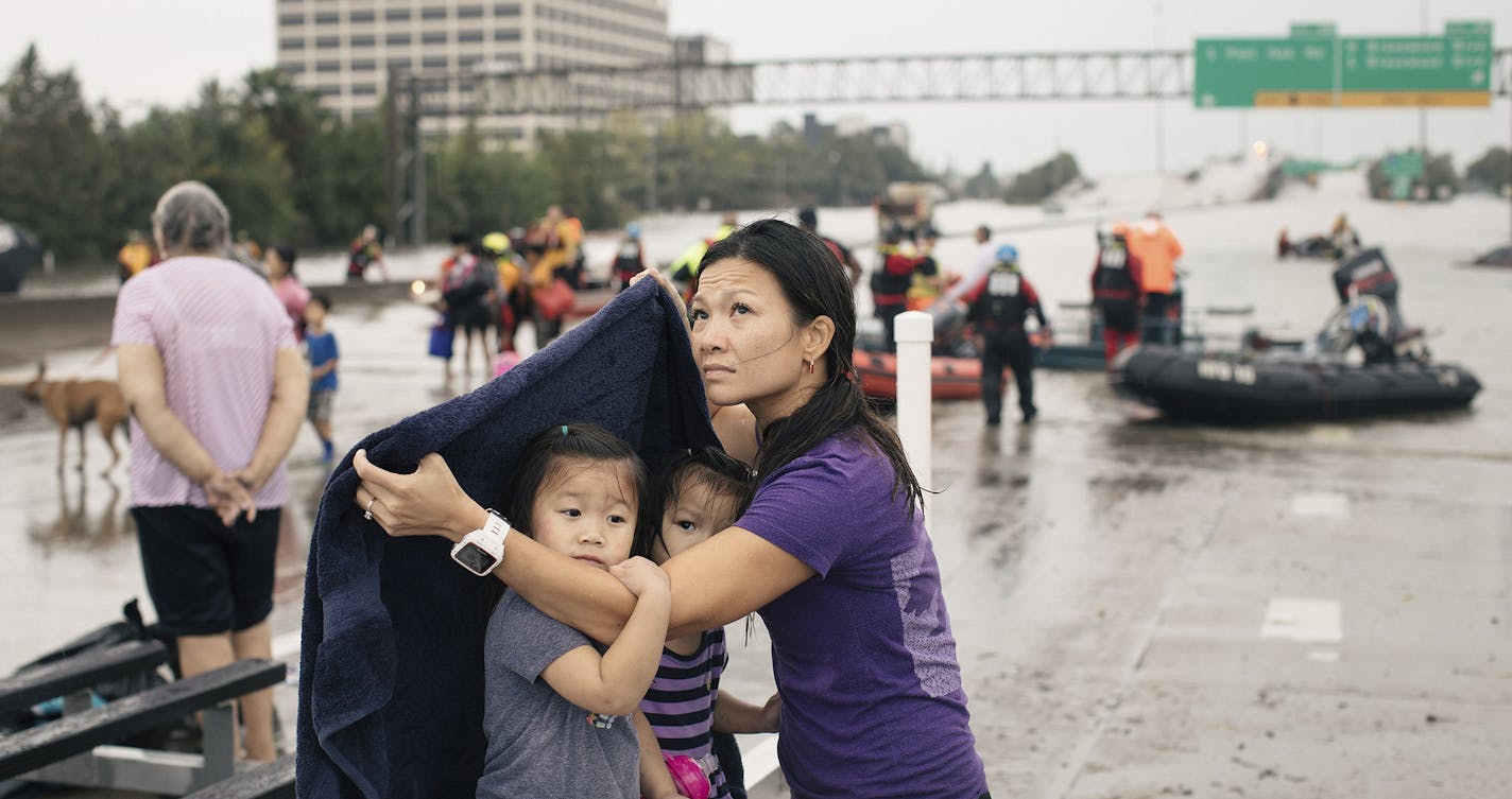 Vi Tran uses a blanket to shield her daughters Olivia, 4, and Eva, 2, from the rain after being evacuated from Houston's Meyerland area, Aug. 27, 2017. On Sunday, Harvey, now a tropical storm, pounded the region with torrential rains, and the National Weather Service forecasts rainfall of 15 to 25 inches through Friday, with as much as 50 inches in a few areas. (Alyssa Schukar/The New York Times) ORG XMIT: MIN2017082813104521