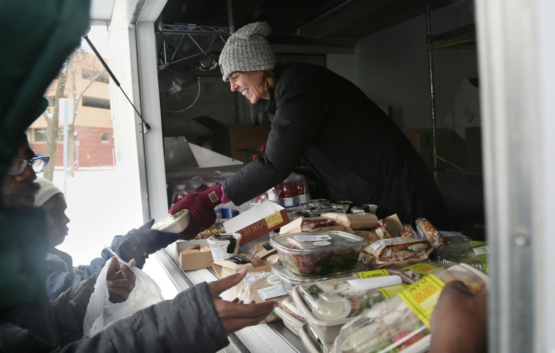 The local non-profit, Loaves and Fishes has partnered with the MSP Airport and concessionaire HMS Host to donate ready-to-eat meals not purchased at the airport, that would otherwise be thrown away, to the homeless near the Dorothy Day Center Thursday, Dec. 28, in St. Paul, MN. Here, Cathy Maes, Loaves and Fishes executive director, hands out sandwiches.