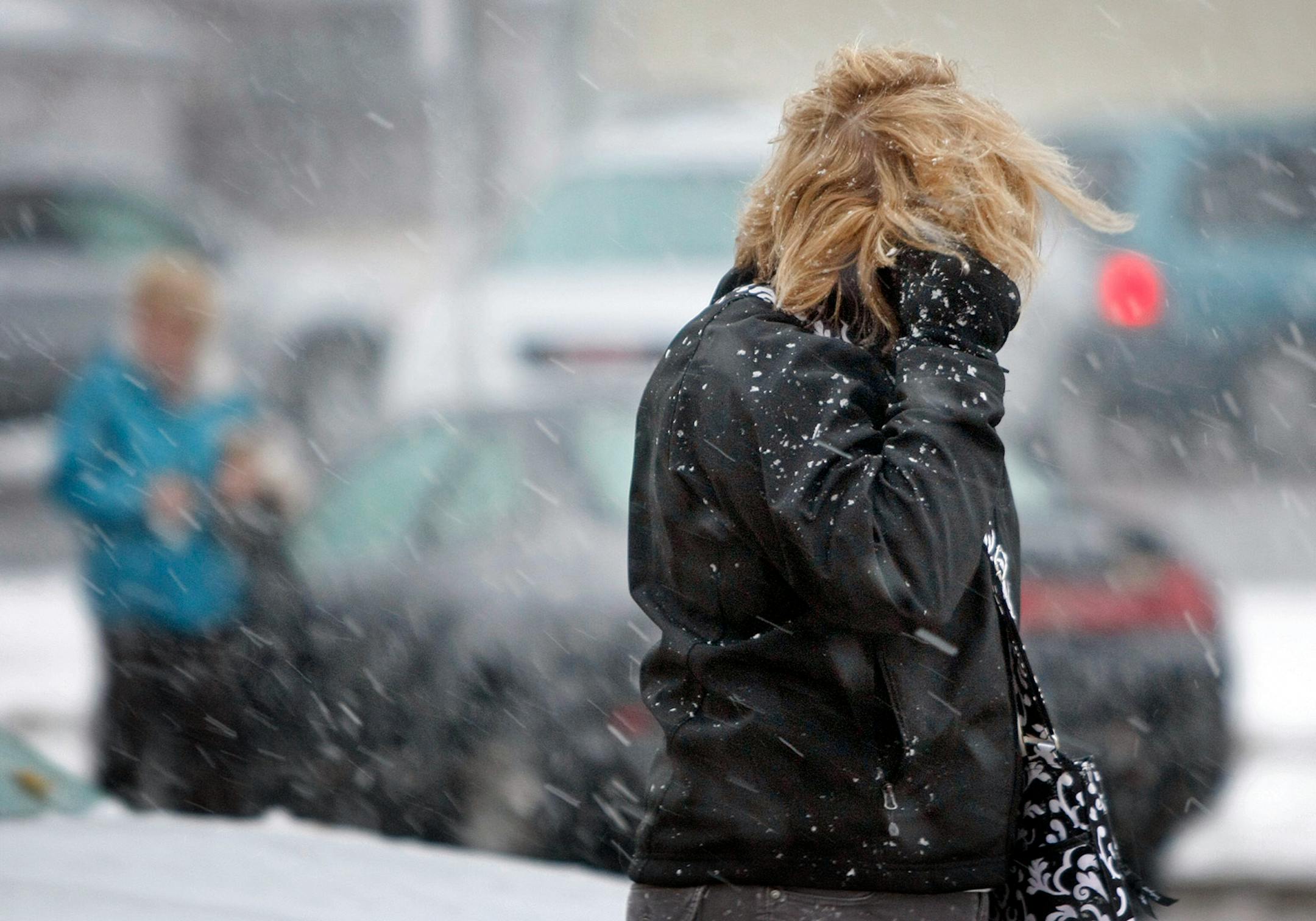 A pedestrian shields her face from the wind and snow in West Fargo, N.D., on Thursday, Oct. 4, 2012. An early fall snowstorm swept into eastern North Dakota's Red River Valley early Thursday, causing travel delays.