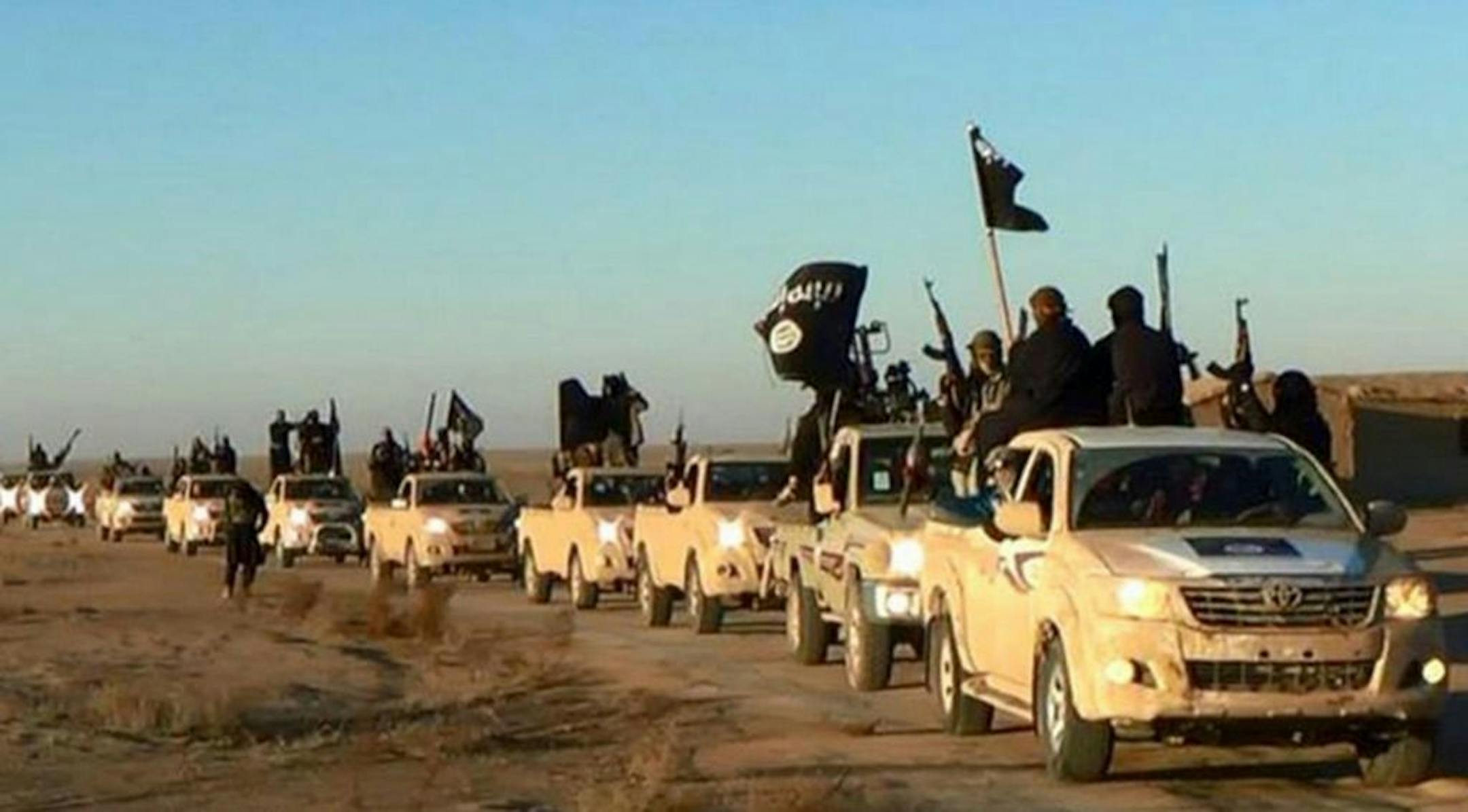 FILE - In this undated file photo released online in the summer of 2014 on a militant social media account, which has been verified and is consistent with other AP reporting, militants of the Islamic State group hold up their weapons and wave its flags on their vehicles in a convoy on a road leading to Iraq, in Raqqa, Syria. The extremist group that once bragged about minting its own currency is now accepting only U.S. dollars in Raqqa, slashing salaries across the board and imposing �exit fees�