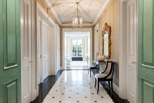 A log foyer with apple green doors on either side of the entry and a window at the end.