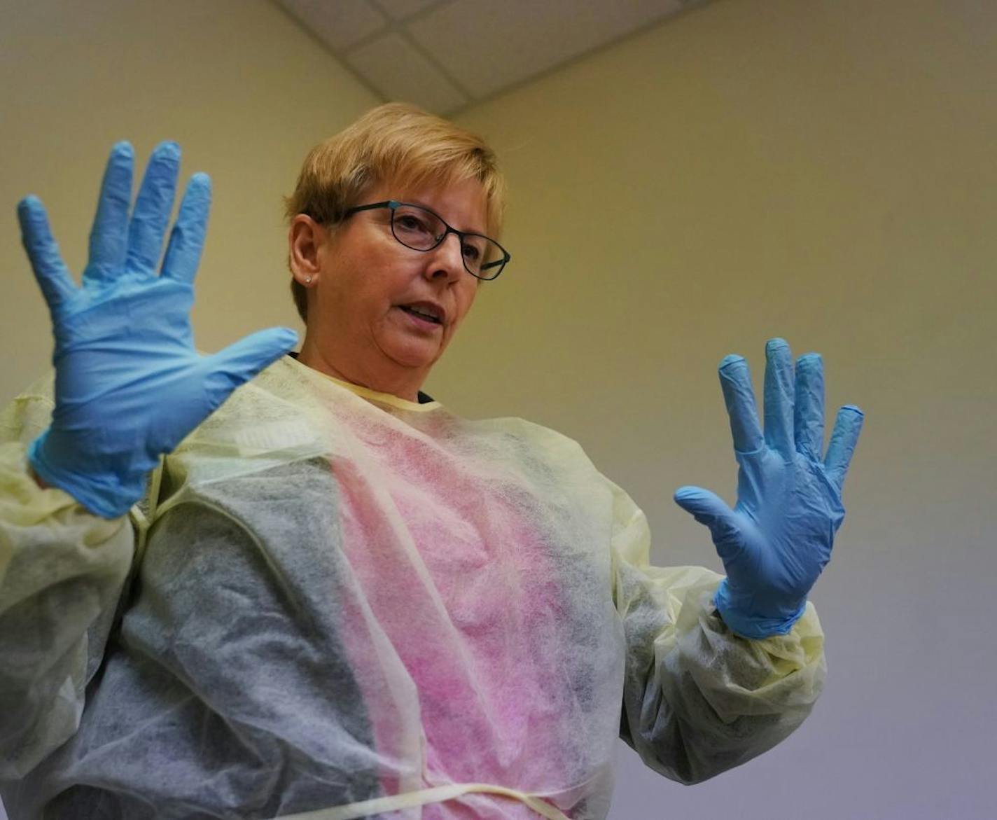 Barbara Sager, RN and education training specialist, led a class of Presbyterian Homes employees on infection control in response to the COVID-19 outbreak. In this photo, Sager demonstrated the proper way to put on a gown and gloves.