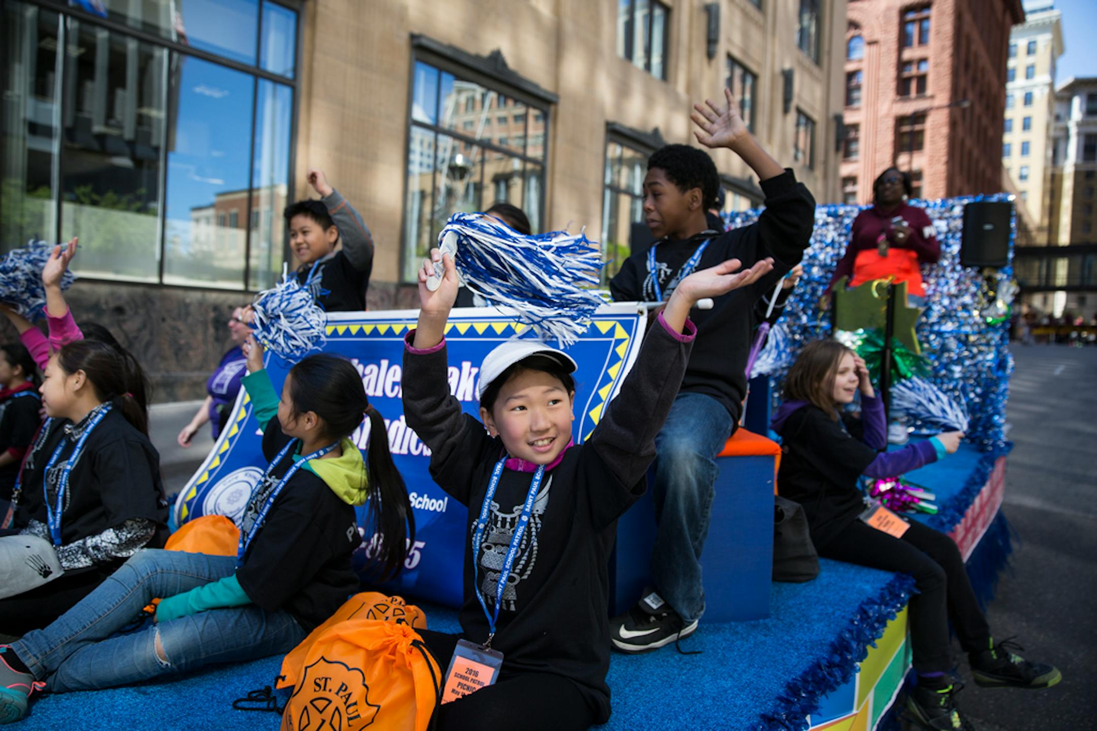 Fourth grader Kanah Vue, center, a member of the school patrol for Phalen Lake Hmong Studies Magnet School waves during the parade. The school patrol for Phalen Lake Hmong Studies Magnet School were the winners of the Winterhalter Outstanding Patrol Award, and get to ride on the float with St. Paul Interim Police Chief Kathy Wuorinen as part of their prize during the parade. ] (Leila Navidi/Star Tribune) leila.navidi@startribune.com BACKGROUND INFORMATION: During the St. Paul School Patrol Parad
