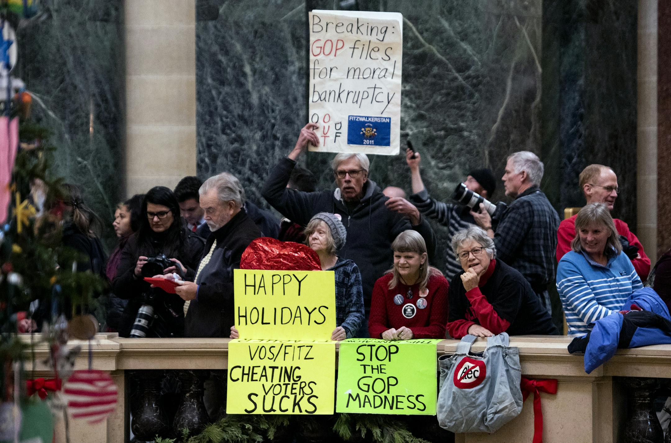 Protestors at the state Capitol in Madison hold up signs on Tuesday, Dec. 4, 2018, as the Wisconsin State Assembly debates a series of bills that would strip the incoming Democratic governor of power. After a rancorous, sleepless night of debate, Republican lawmakers early Wednesday pushed through the sweeping set of bills, which Democrats vehemently opposed and protesters chanted their anger over. (Lauren Justice/The New York Times)