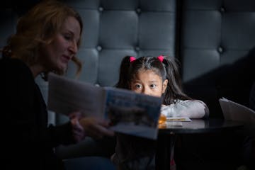 Teacher Julia Furness Rubio, left, reads with a student during a field trip to the downtown library in Minneapolis, Minn., on Friday, Dec. 22, 2023.  