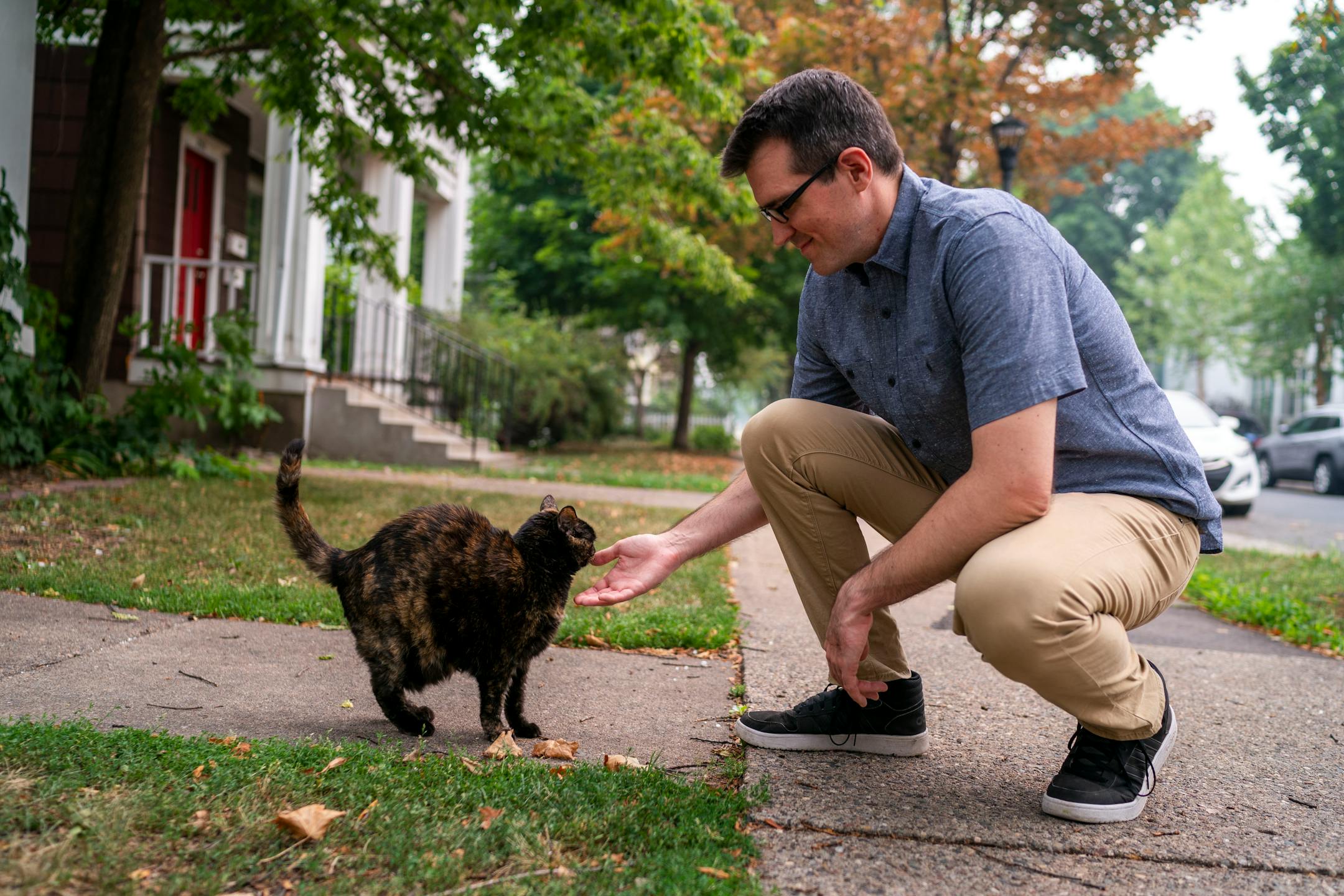 John Edwards, organizer, holds his hand out to Fish, a 13 year-old cats belonging to Zach Randolph, while going for a walk to looks for cats in the neighborhood on Thursday, July 29, 2021, in Minneapolis. ] ANTRANIK TAVITIAN • anto.tavitian@startribune.com