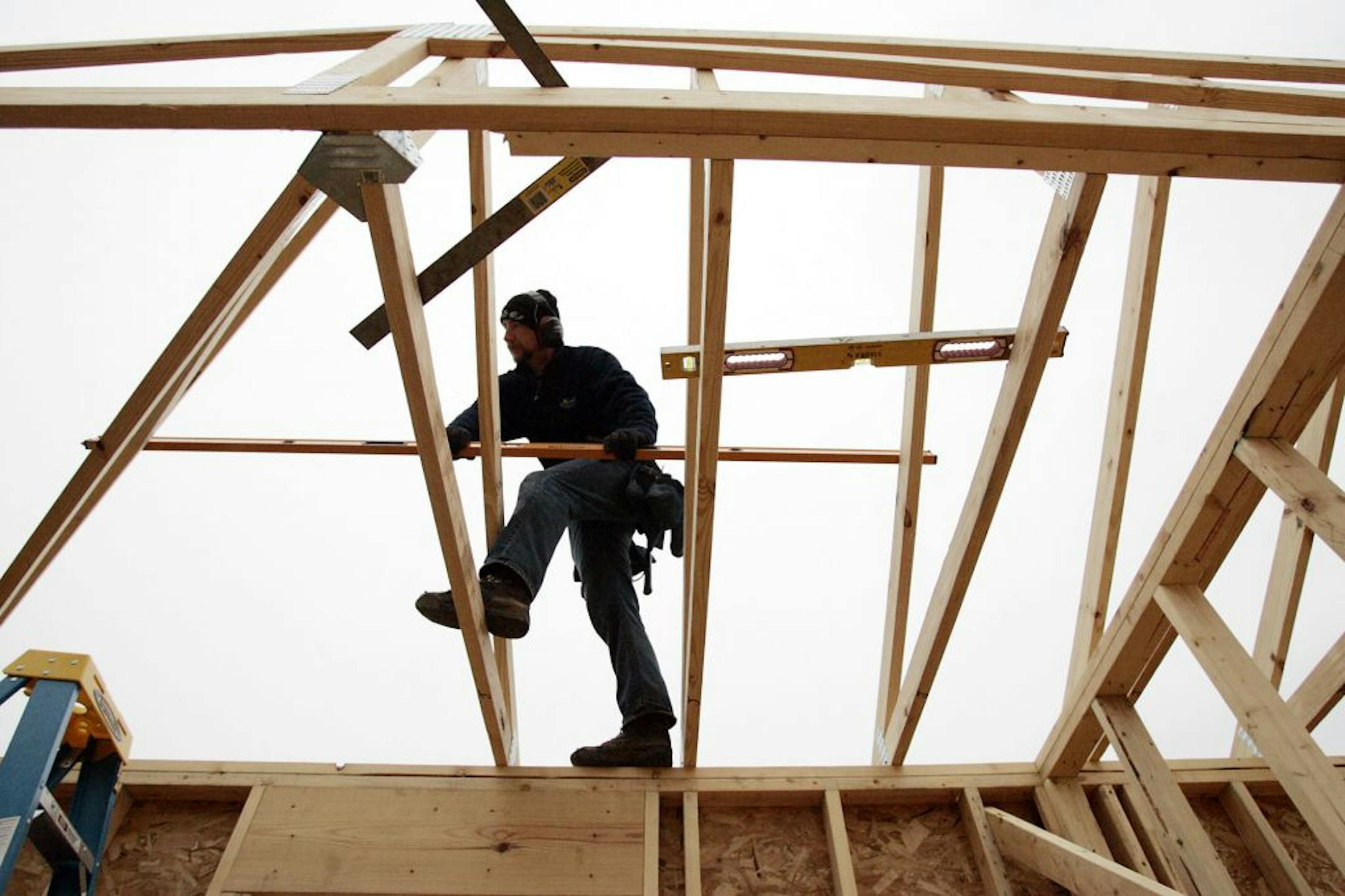 In this Nov.3, 2011 photo, Jim Weiler, of Jim Weiler Construction, sets a roof truss on a home under construction in LaPorte, Ind. Rising interest from would-be buyers is leaving U.S. homebuilders less pessimistic about the housing market. But tighter lending standards are still keeping many potential buyers from purchasing new homes.