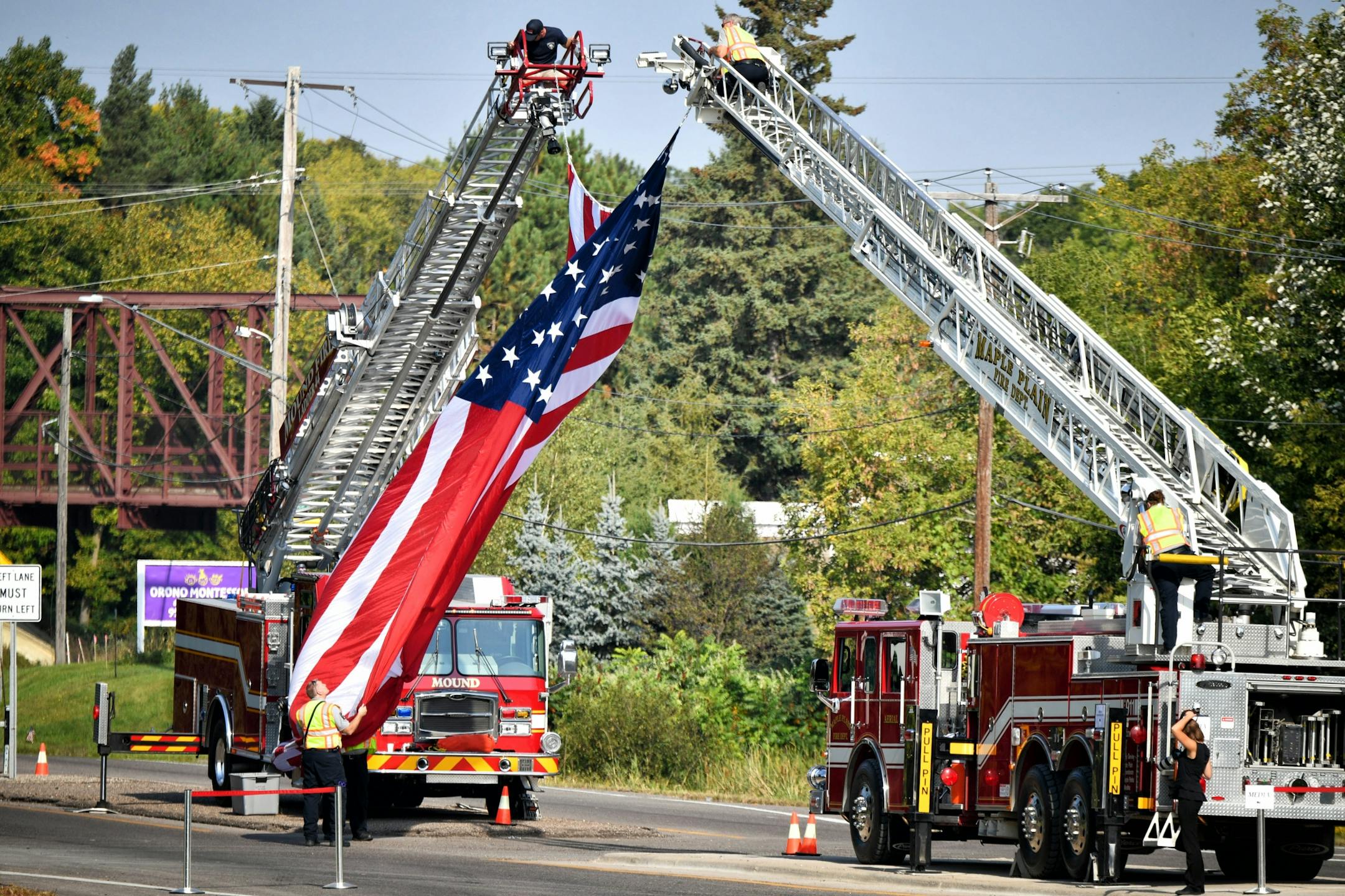 An American flag is suspended at the entrance to Summit Park Cemetery before the burial of Wayzata Officer William Mathews. The Trucks are from Mound and Maple Plain fire Departments.