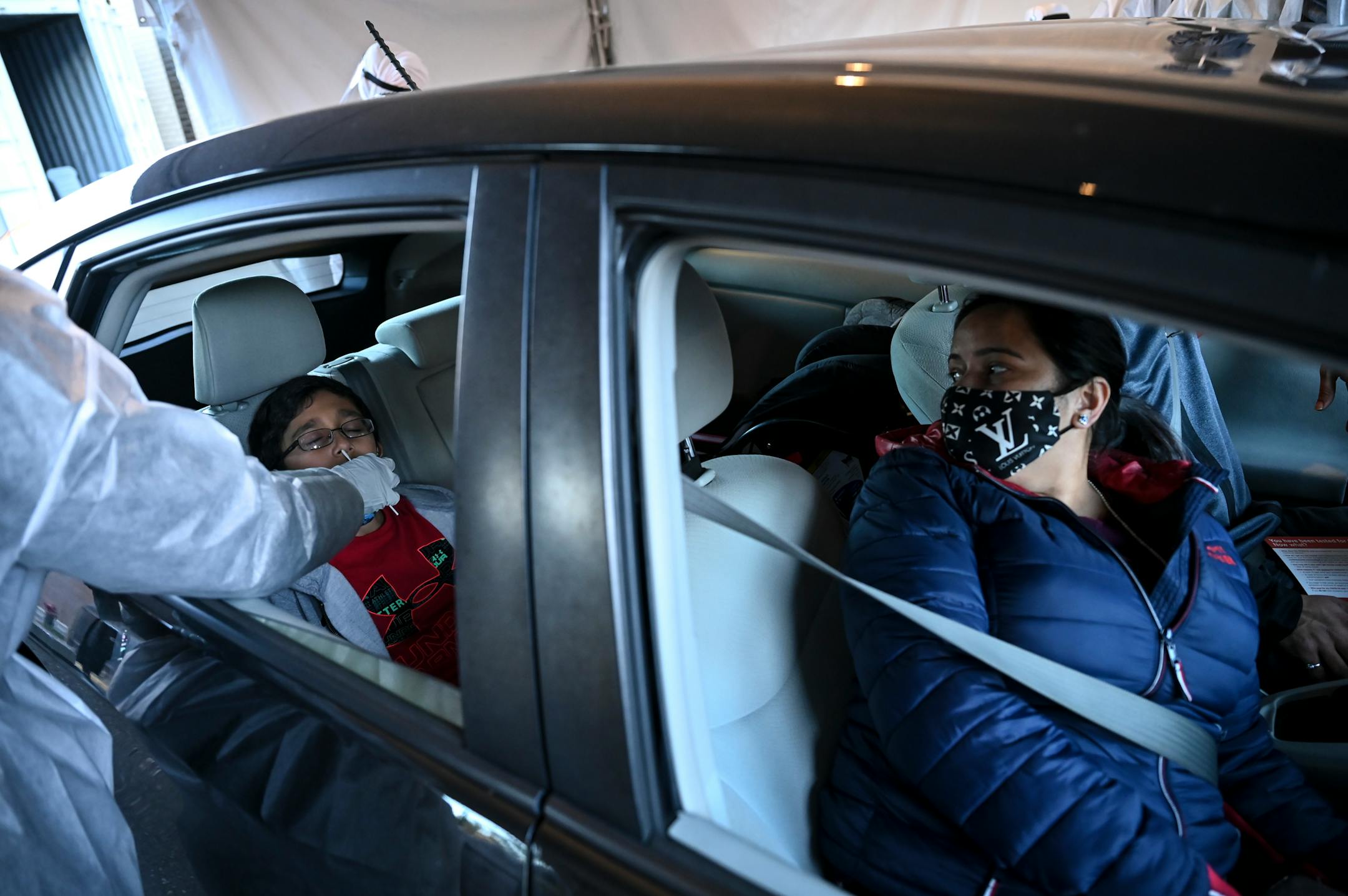 Nidhi Joshi, right, watched as her 9-year old son, Bhruv was tested for COVID-19 at North Memorials drive-up testing site. Joshi says she's been feeling under the weather and wanted to get tested with her son, also displaying some cold symptoms, "just to be safe."