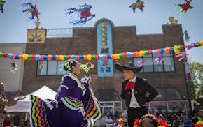Serita Huerta, left, and Alex Molina dance on the Los Alegres Bailadores float during the Cinco de Mayo parade down Lake Street in Minneapolis on May