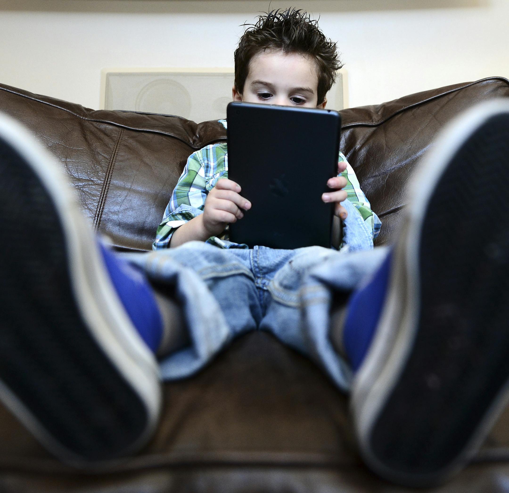 Maddon Segall, 3, plays on an iPad mini in his home in Livingston, N.J., Dec. 19, 2013. American children's passion for toys seems to be fading at an earlier age than ever, and retailers like Toys "R" Us have adjusted to the rapid shift in preference to tablets, computers and cellphones by retooling as electronics stores themselves. (Ben Solomon/The New York Times)