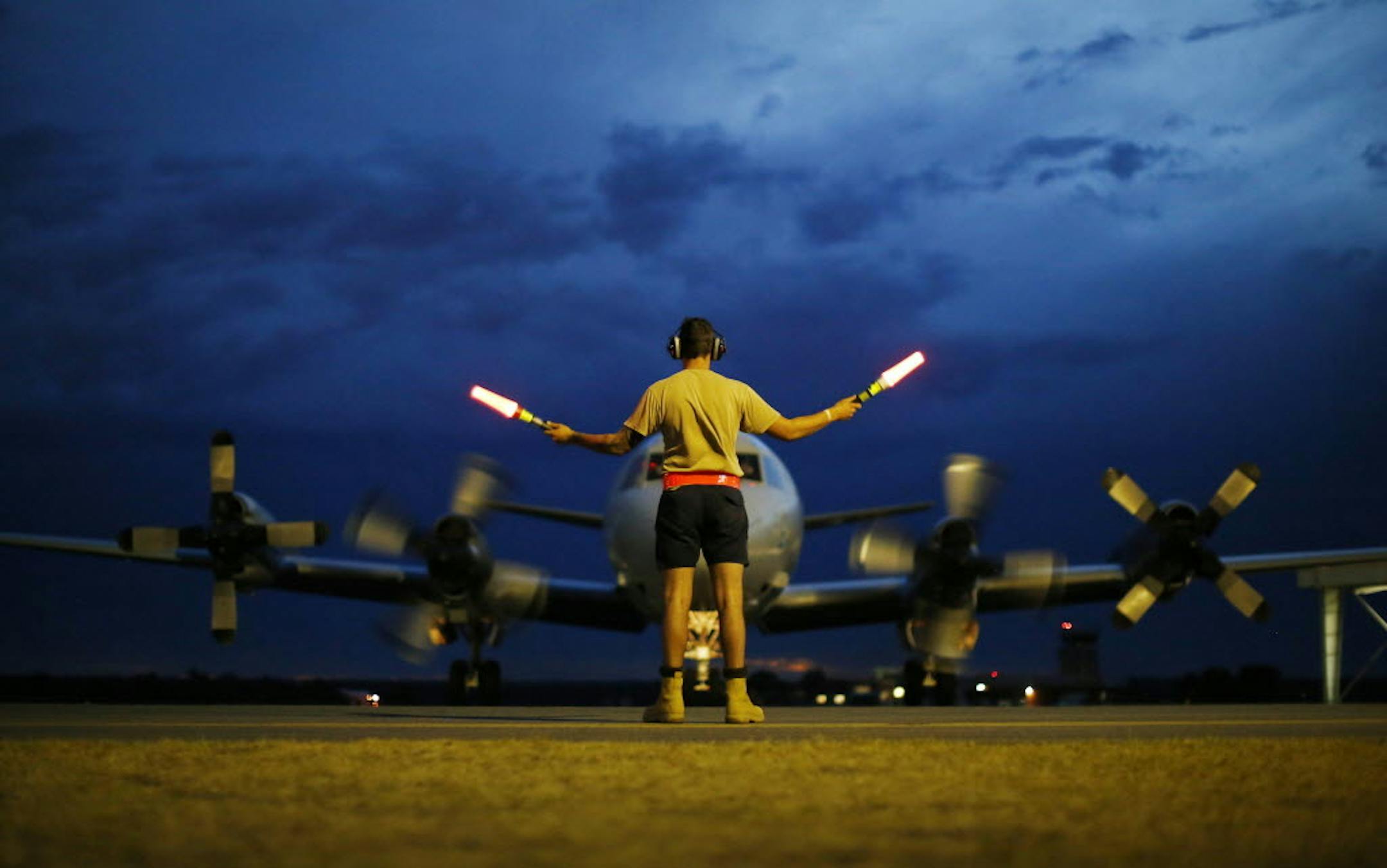 March 24, 2014: A ground controller guides a Royal Australian Air Force AP-3C Orion to rest after sunset upon its return from a search for the missing Malaysia Airlines Flight 370, over the Indian Ocean, at the Royal Australian Air Force Base Pearce in Perth, Australia.
