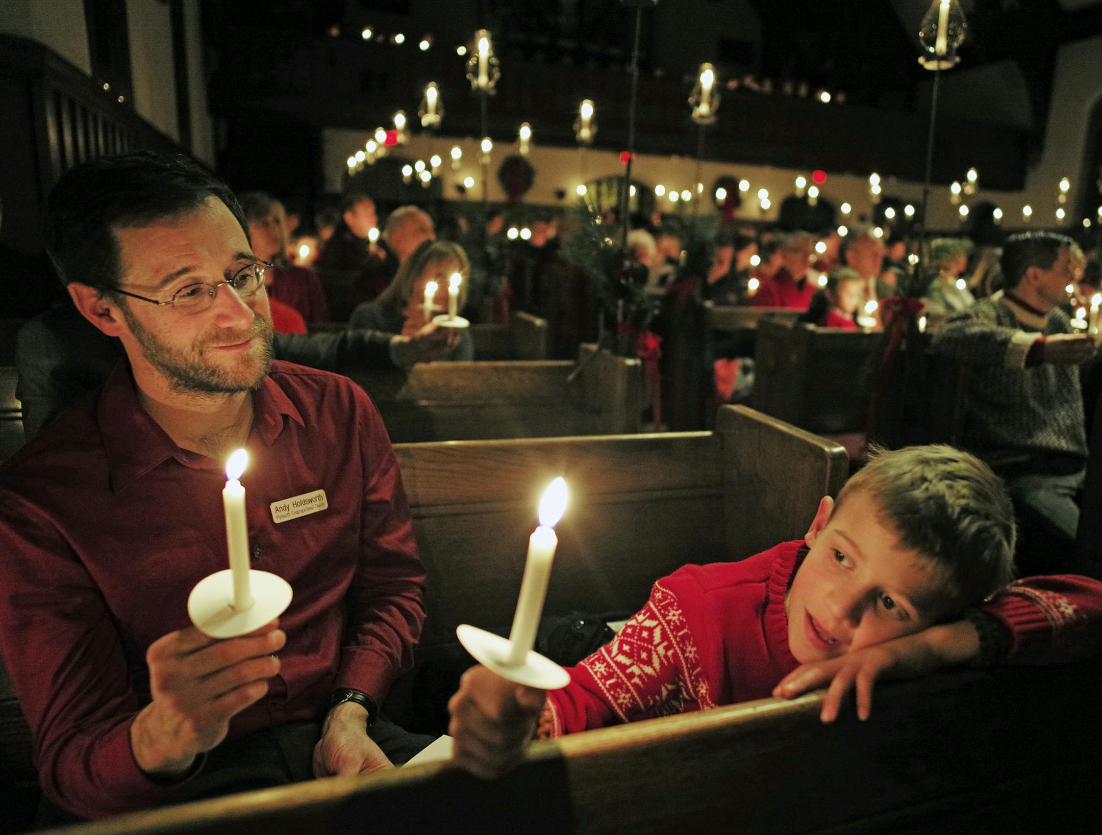 Andy Holdsworth and his son, Theo, 7, held candles during the singing of "Silent Night" at Plymouth Congregational Church in Minneapolis.