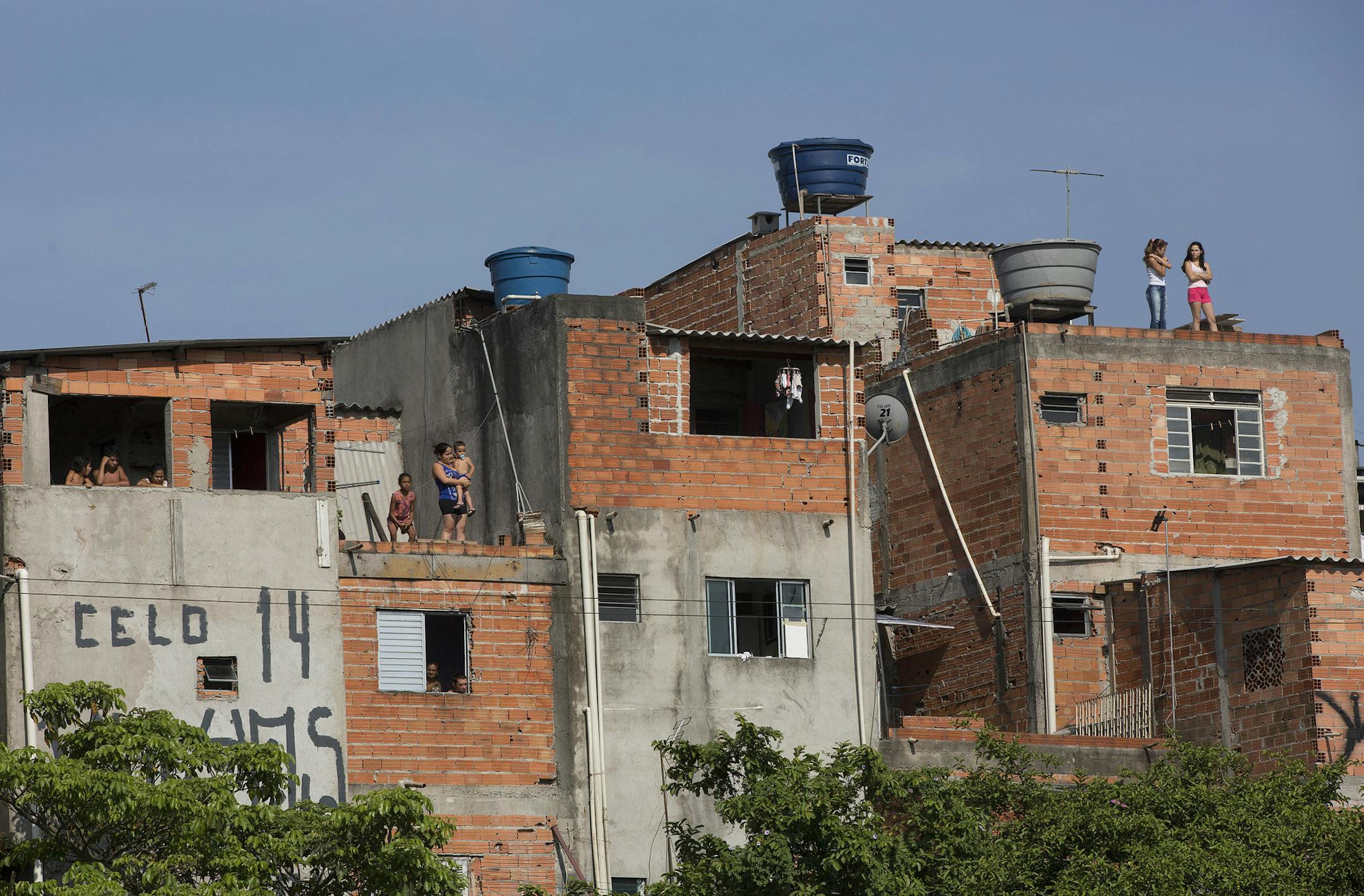 People watch from their homes as Volkswagen workers protest against the layoff of 800 employees, next to the company's plant in Sao Bernardo do Campo, Brazil, Monday, Jan. 12, 2015. Volkswagen said in a recent statement that the company needs to reduce costs at its local factory. Workers there have been striking since Tuesday, halting production at the factory. (AP Photo/Andre Penner)