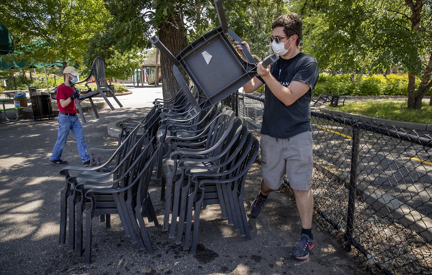 Alex Knutson, right, and Doug Weber, left, organized chairs as Como staff prepared for the reopening of Como Zoo, Friday, July 24, 2020. The Zoo will open July 29 with pandemic protocols in place, such as a one-way route, groups with reservations only. The Como Town theme park will also open. ] ELIZABETH FLORES • liz.flores@startribune.com